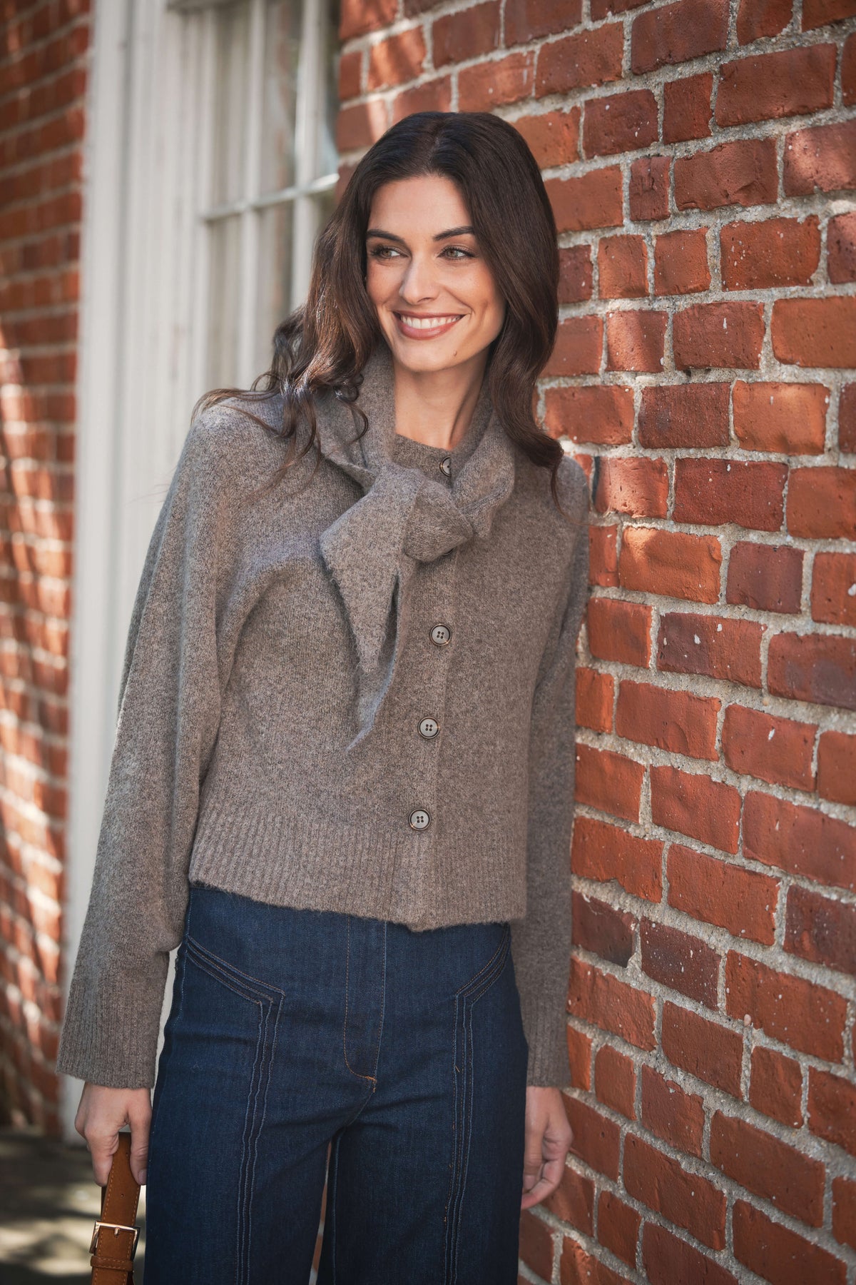 Taupe knit cardigan with detachable scarf collar and button front, worn with dark jeans.