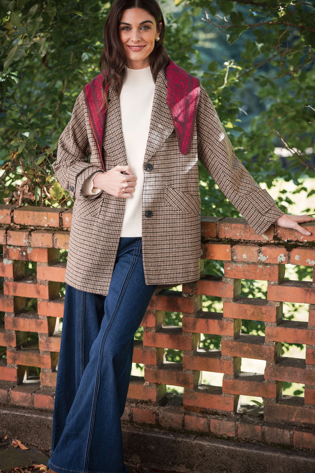 Houndstooth pea jacket with burgundy collar and notched lapels worn over white ribbed sweater and dark jeans.