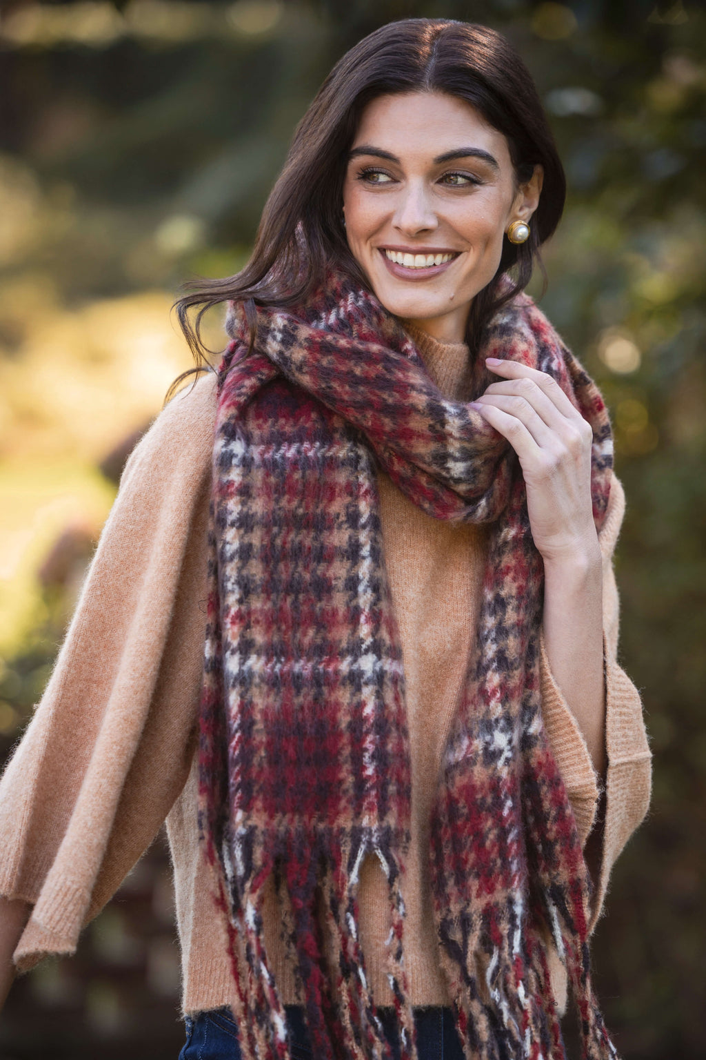 Black, red and white houndstooth pattern scarf with fringe ends, worn draped around shoulders.