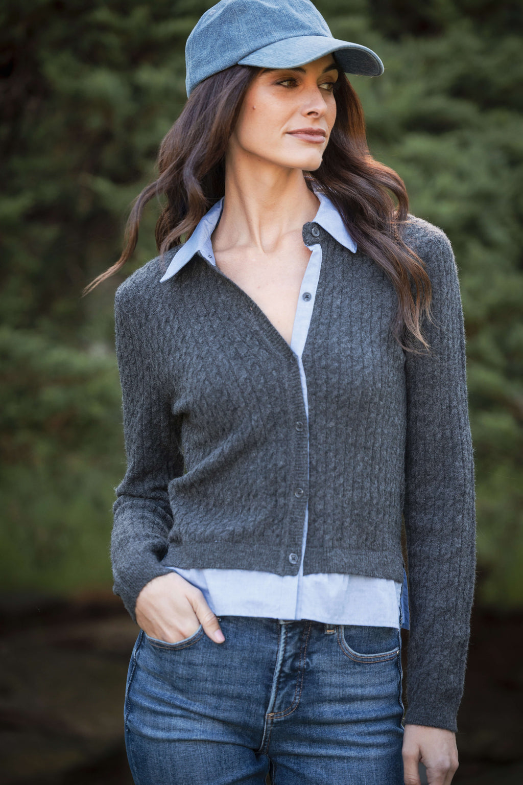 Charcoal knit cardigan with light blue collar and trim, button front, worn with denim jeans and blue cap.