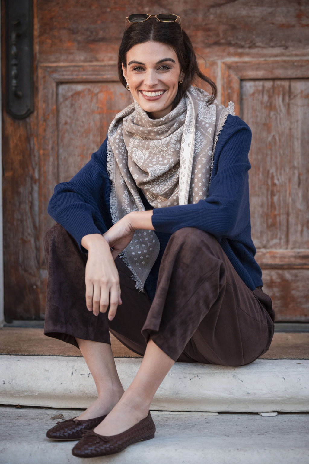 Brown suede pants styled with navy cardigan and patterned scarf.