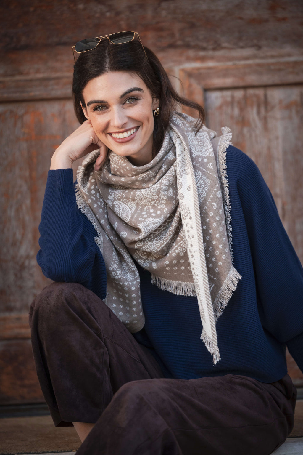 Navy crewneck sweater with dolman sleeves worn with a patterned scarf and brown pants.