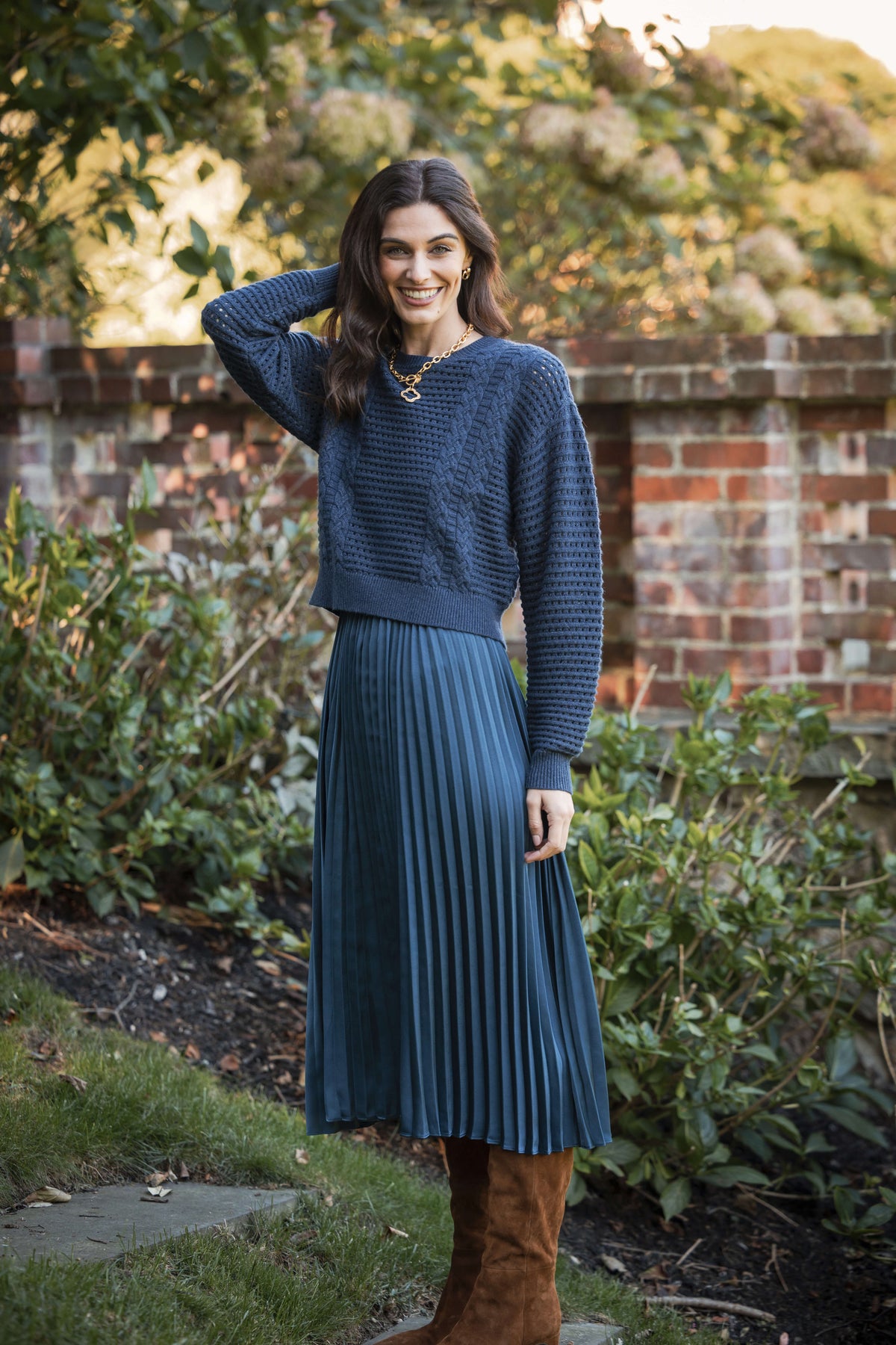 Woman wearing a navy textured cropped sweater over a pleated midi skirt in matching blue.