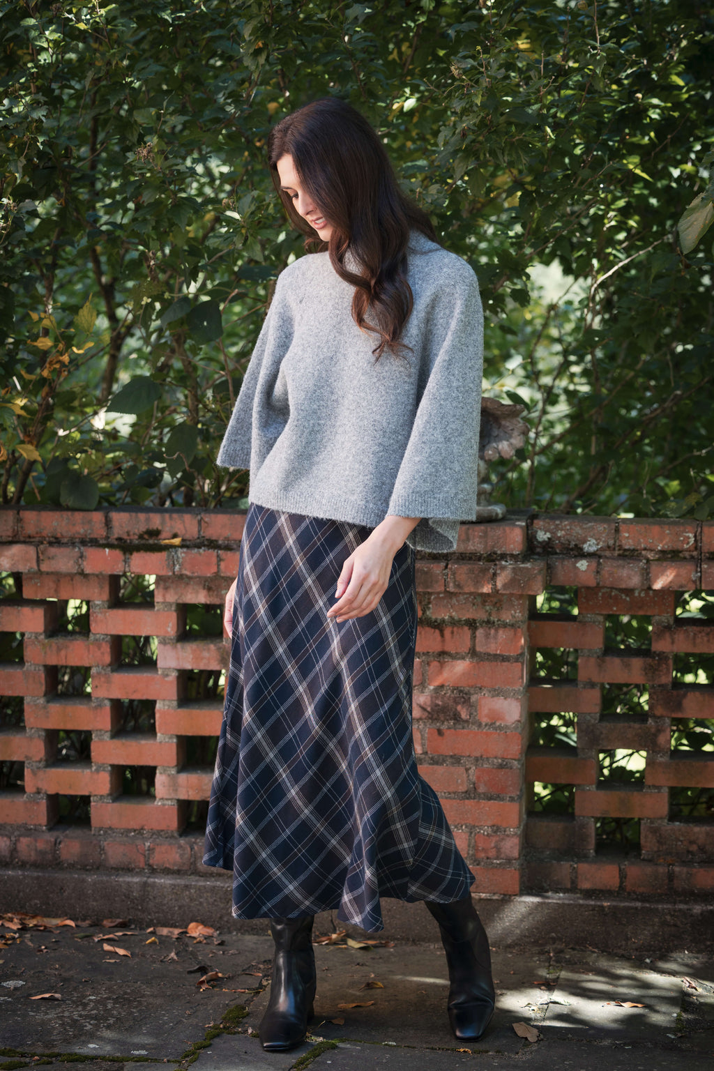 Navy plaid skirt with white windowpane pattern worn with gray sweater and black boots.