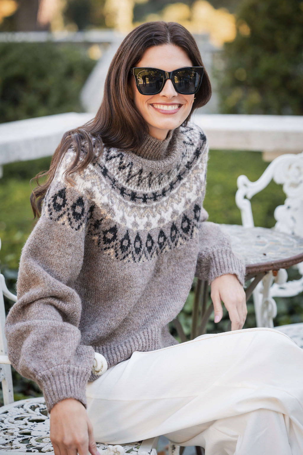 Beige turtleneck sweater with black geometric Fair Isle pattern across chest and shoulders.