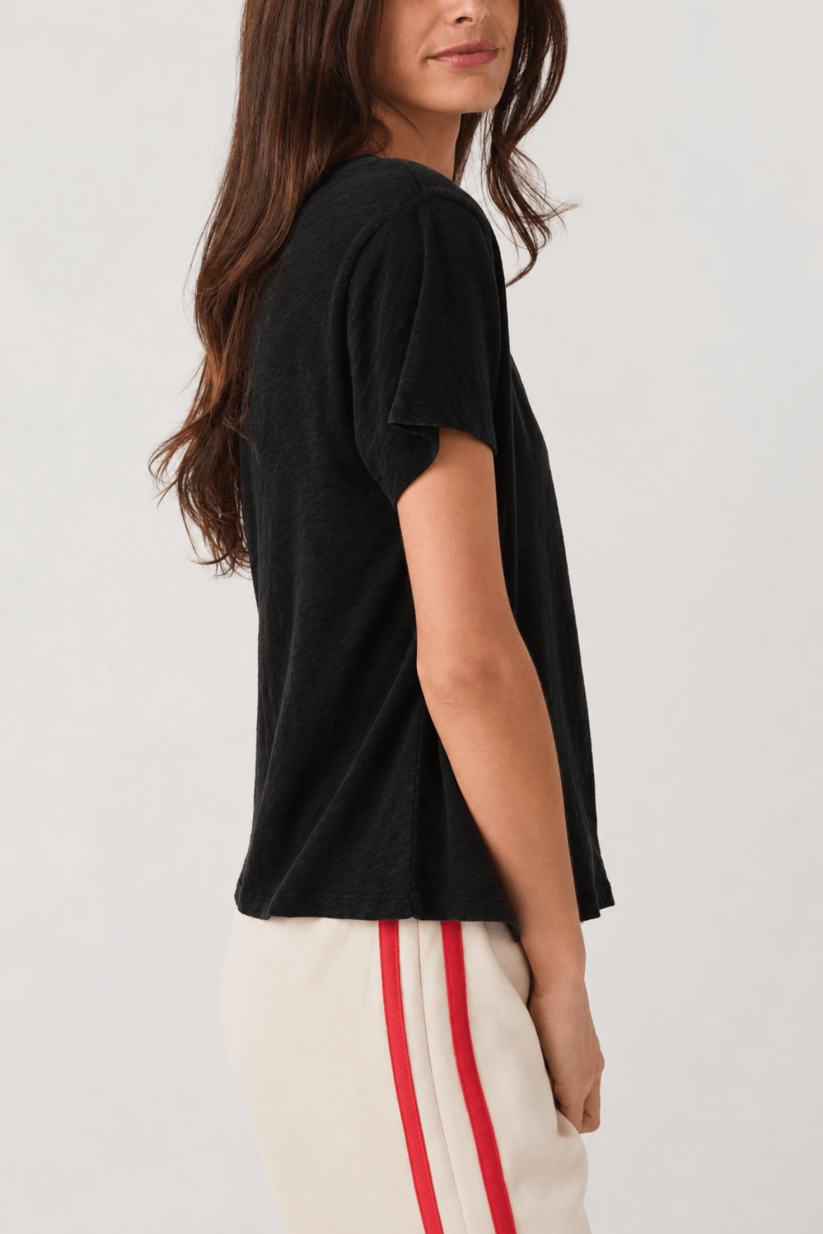 Woman wearing black V-neck short-sleeve tee with relaxed fit, shown from side angle.