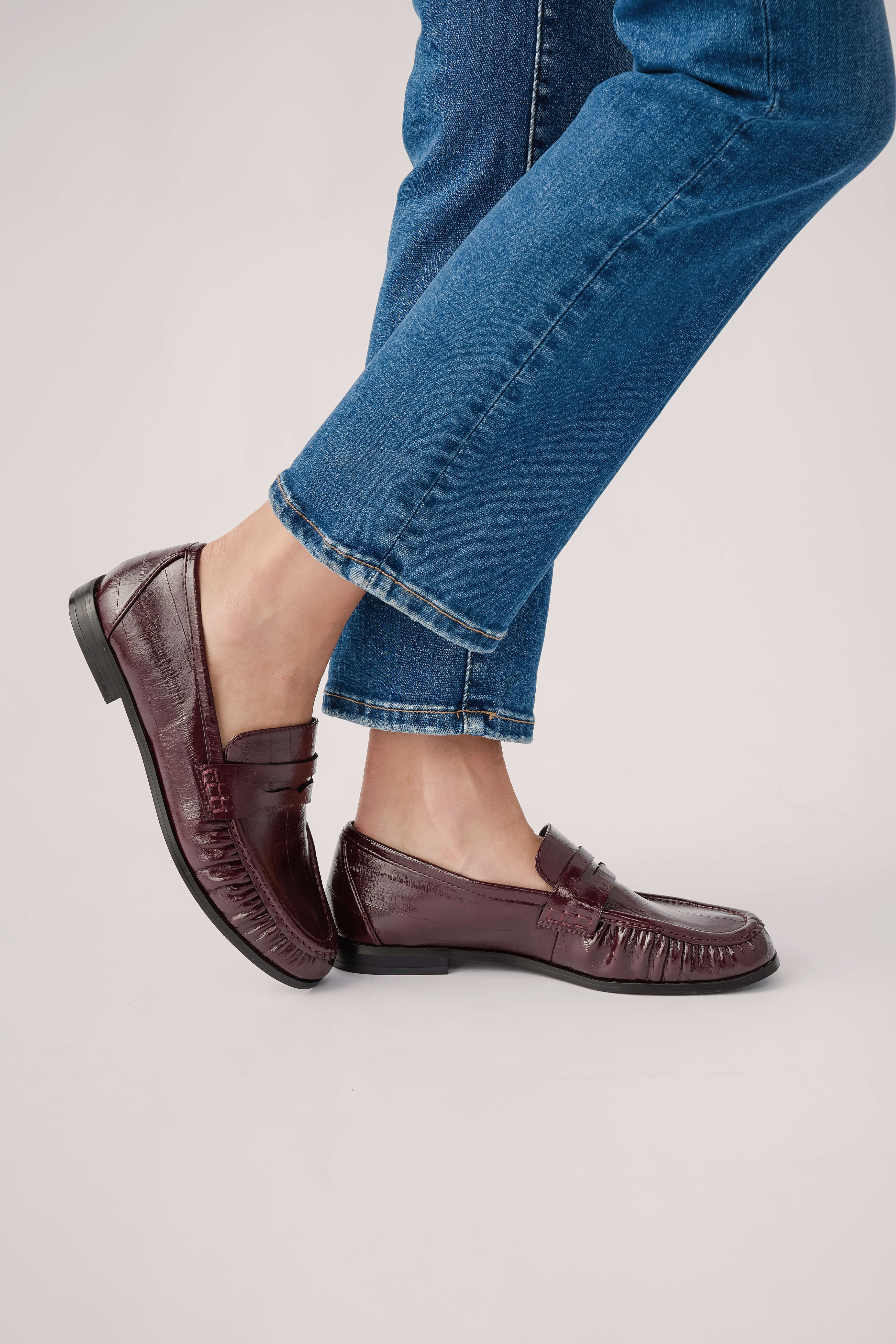 Wine leather loafer on foot, showing moc toe stitching and low heel
