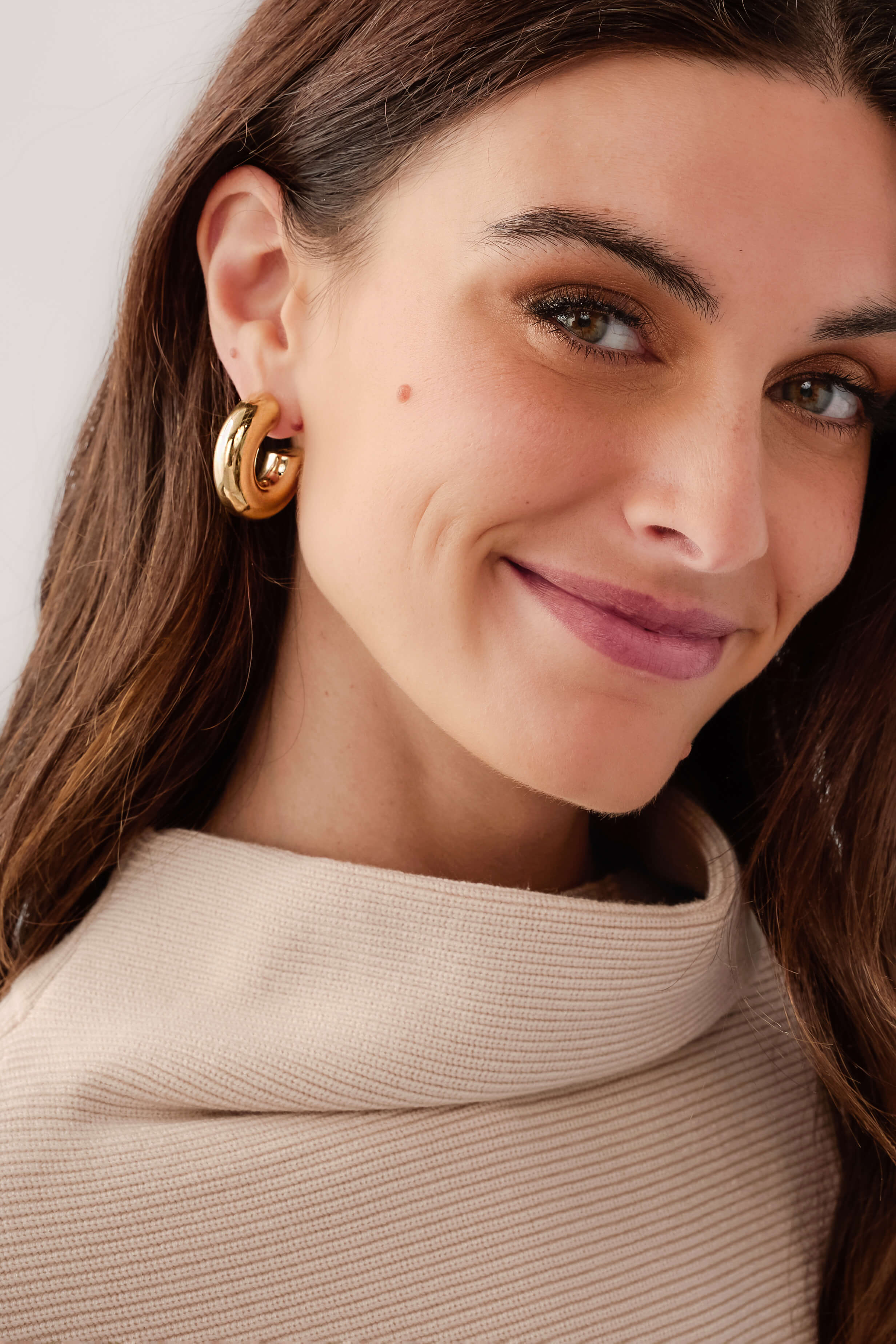 Gold hoop earrings worn on model, polished curved hoops with post back