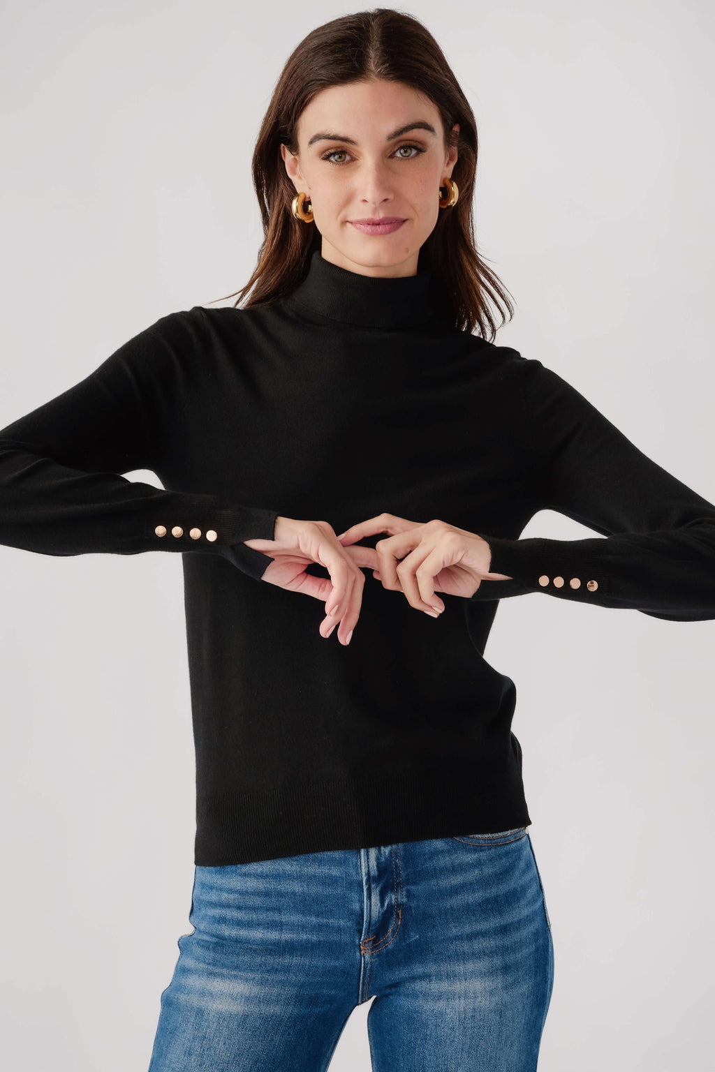 Black knit turtleneck top with ribbed collar and studded button cuffs.