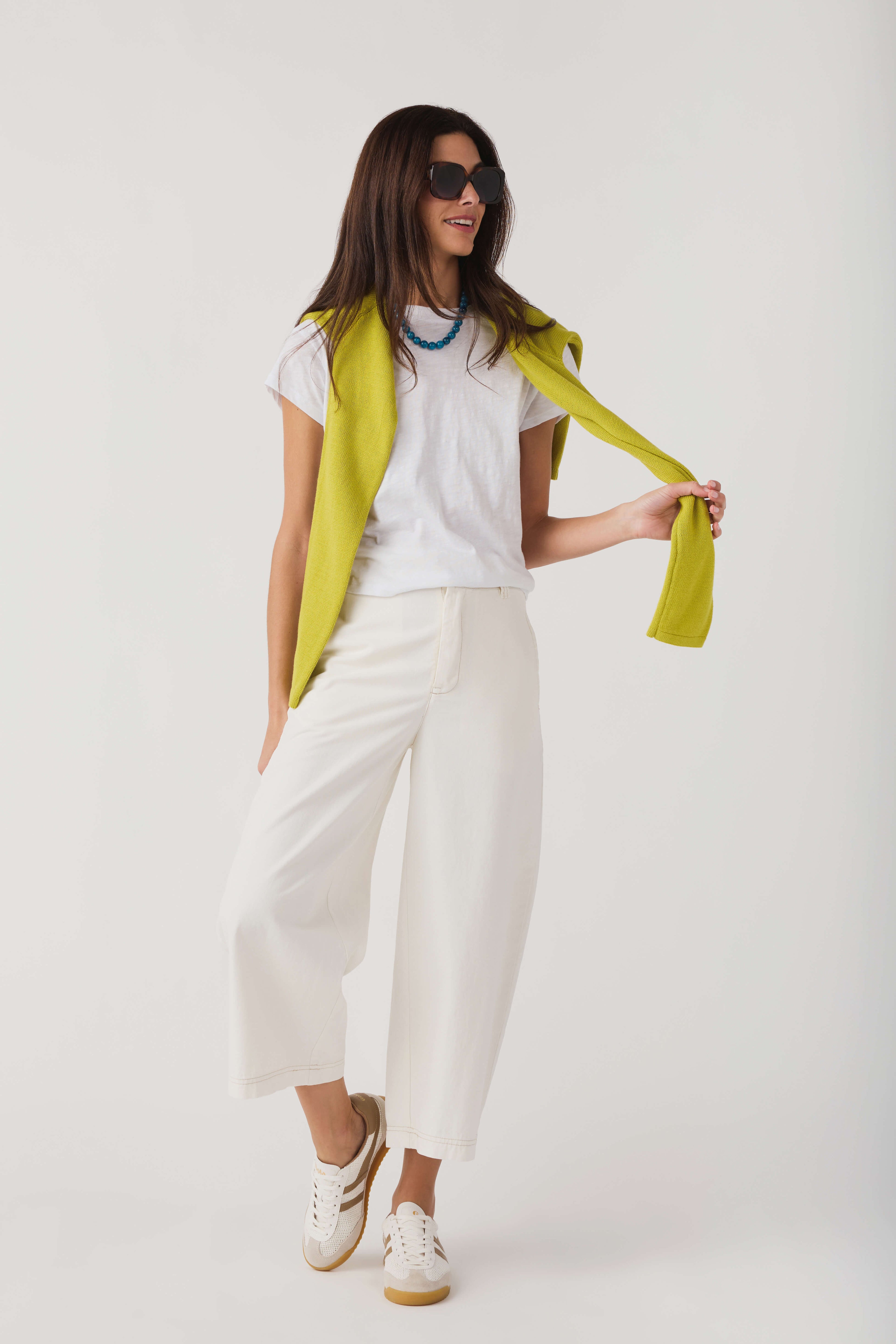 Lime knit crewneck sweater draped over shoulders with long sleeves
