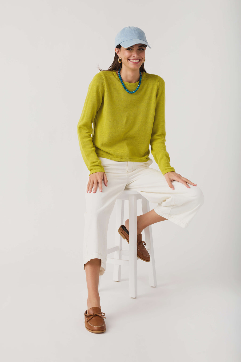 Lime knit crewneck sweater with long sleeves and ribbed hem, seated