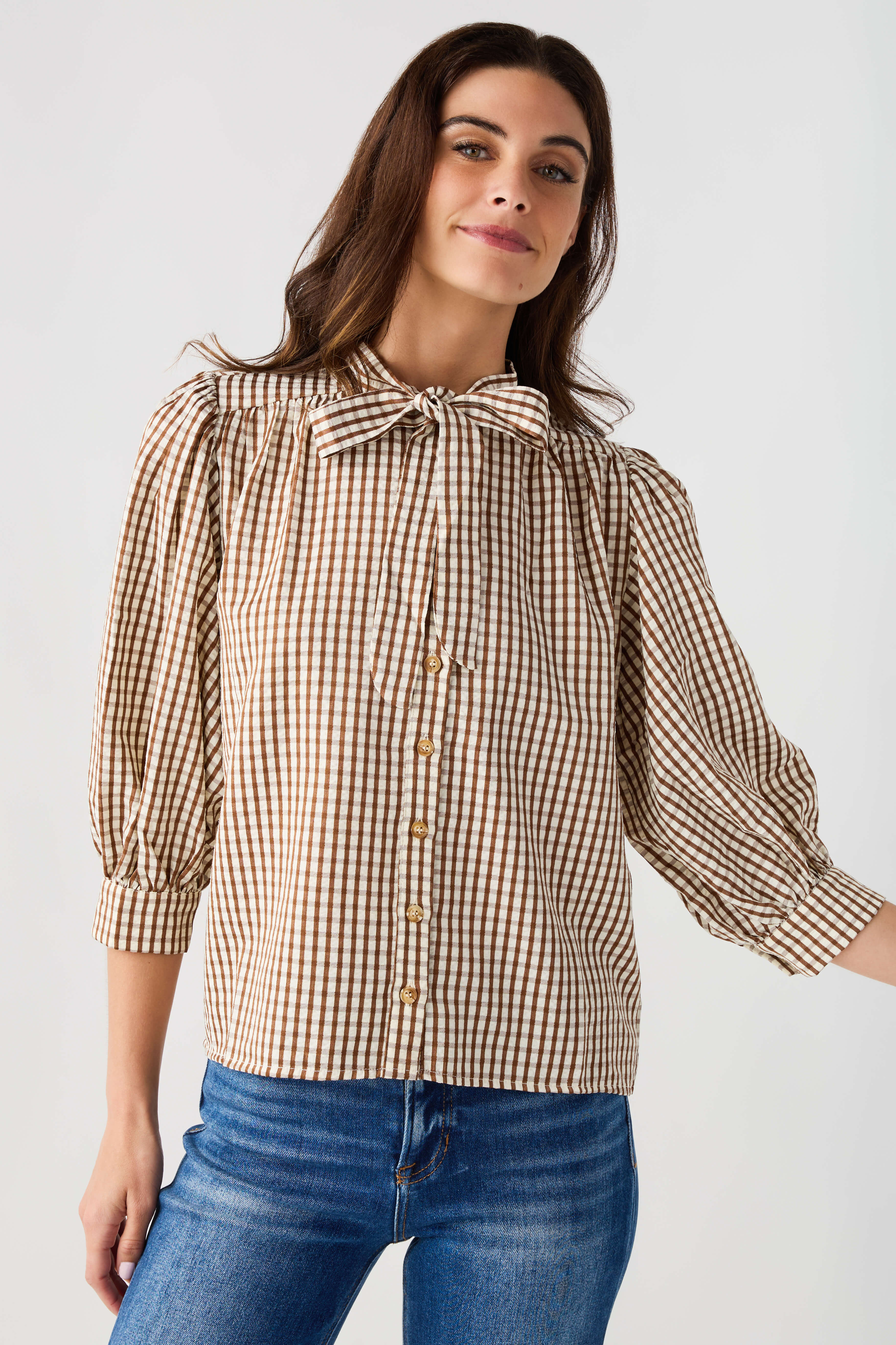 Brown gingham tie-neck blouse with button front and three-quarter puff sleeves