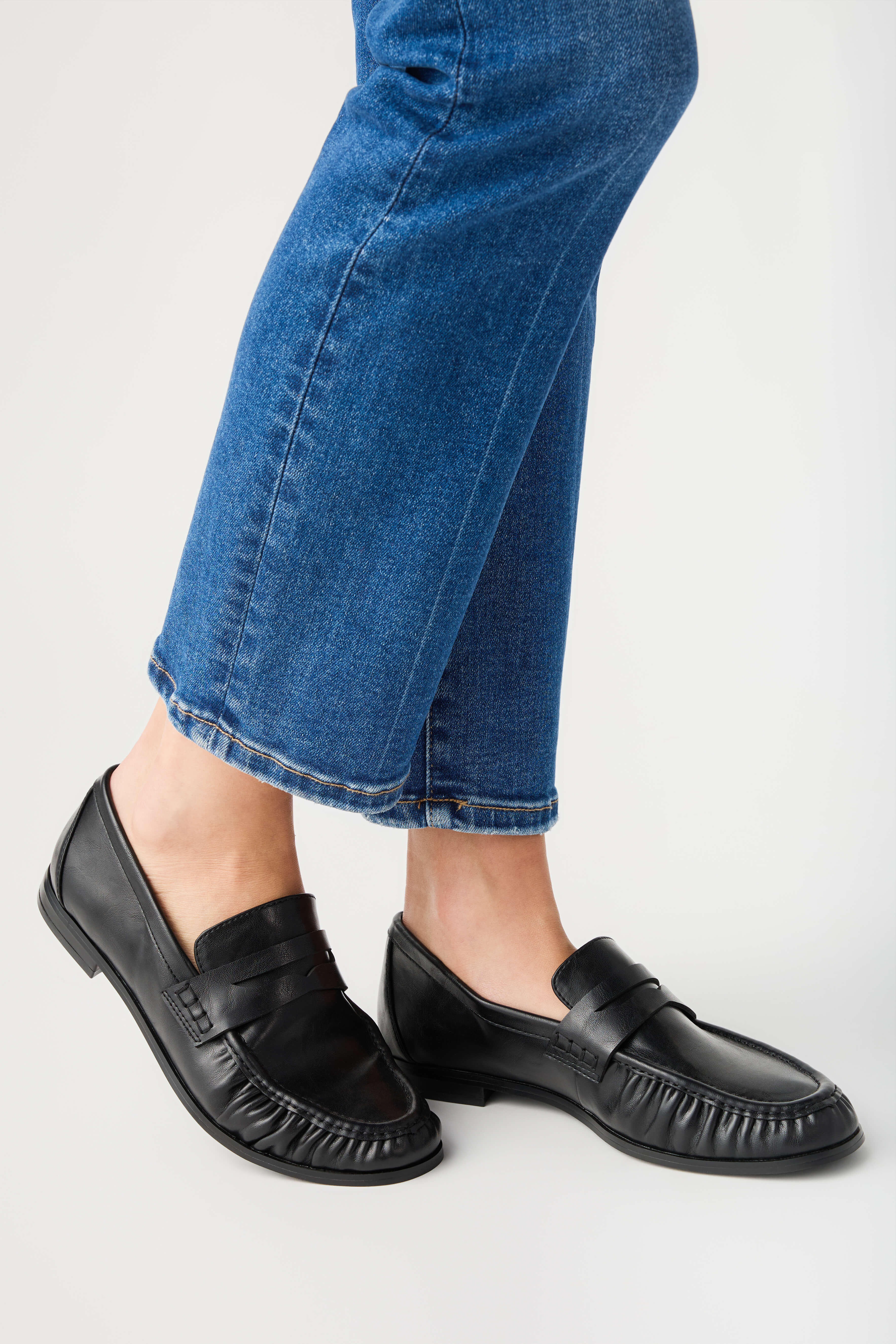Black leather penny loafer with strap detail and moc-style stitching