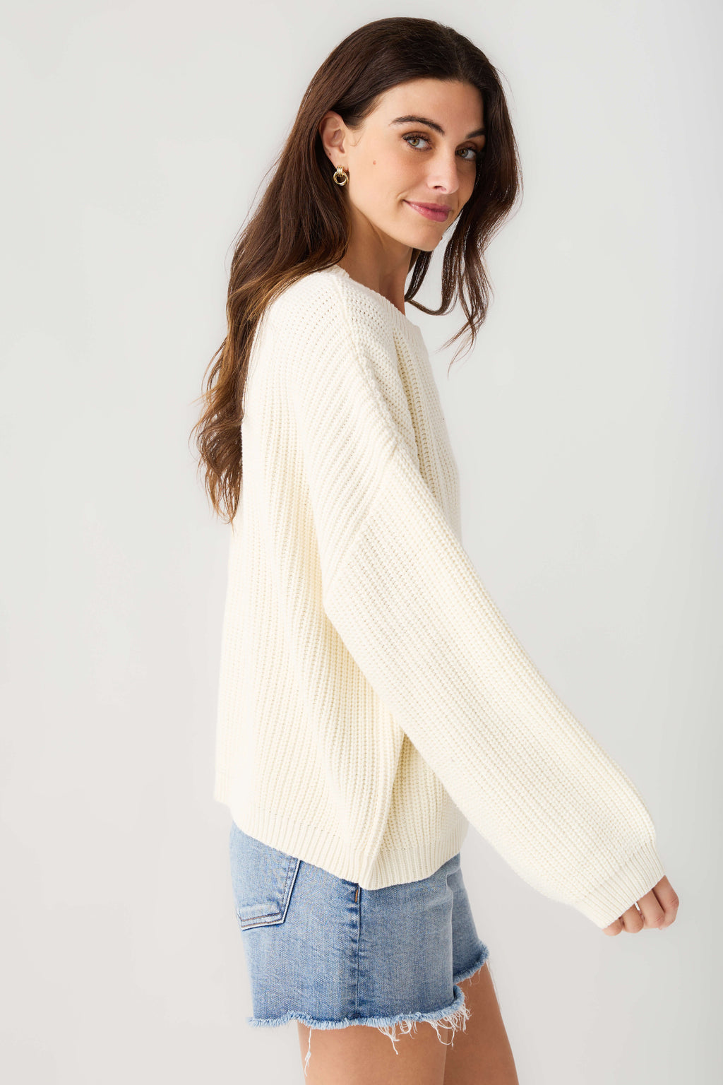 Cream knit pullover top, side view with long sleeves and ribbed hem