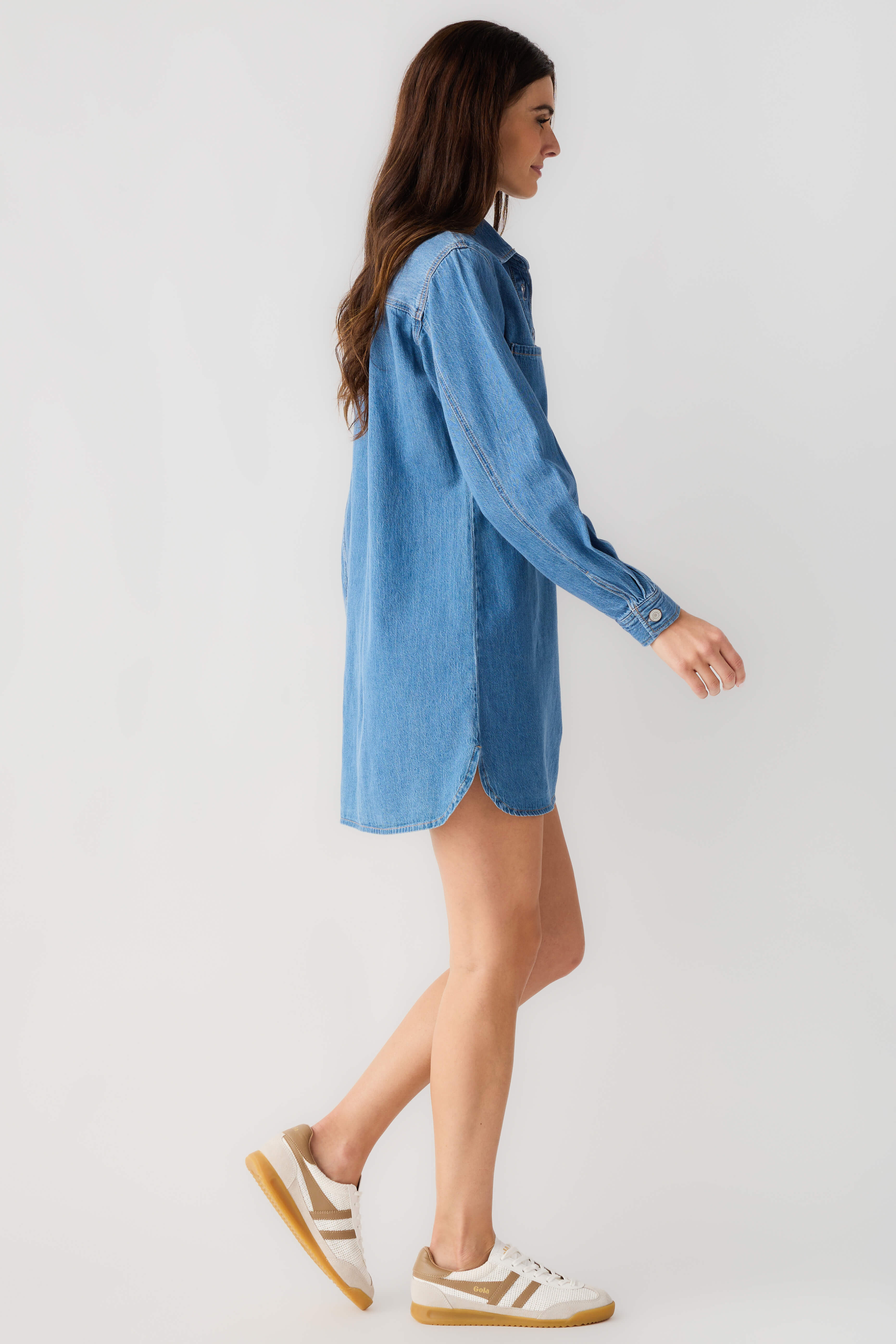 Blue denim shirt dress with collar, button front and long sleeves, side view.