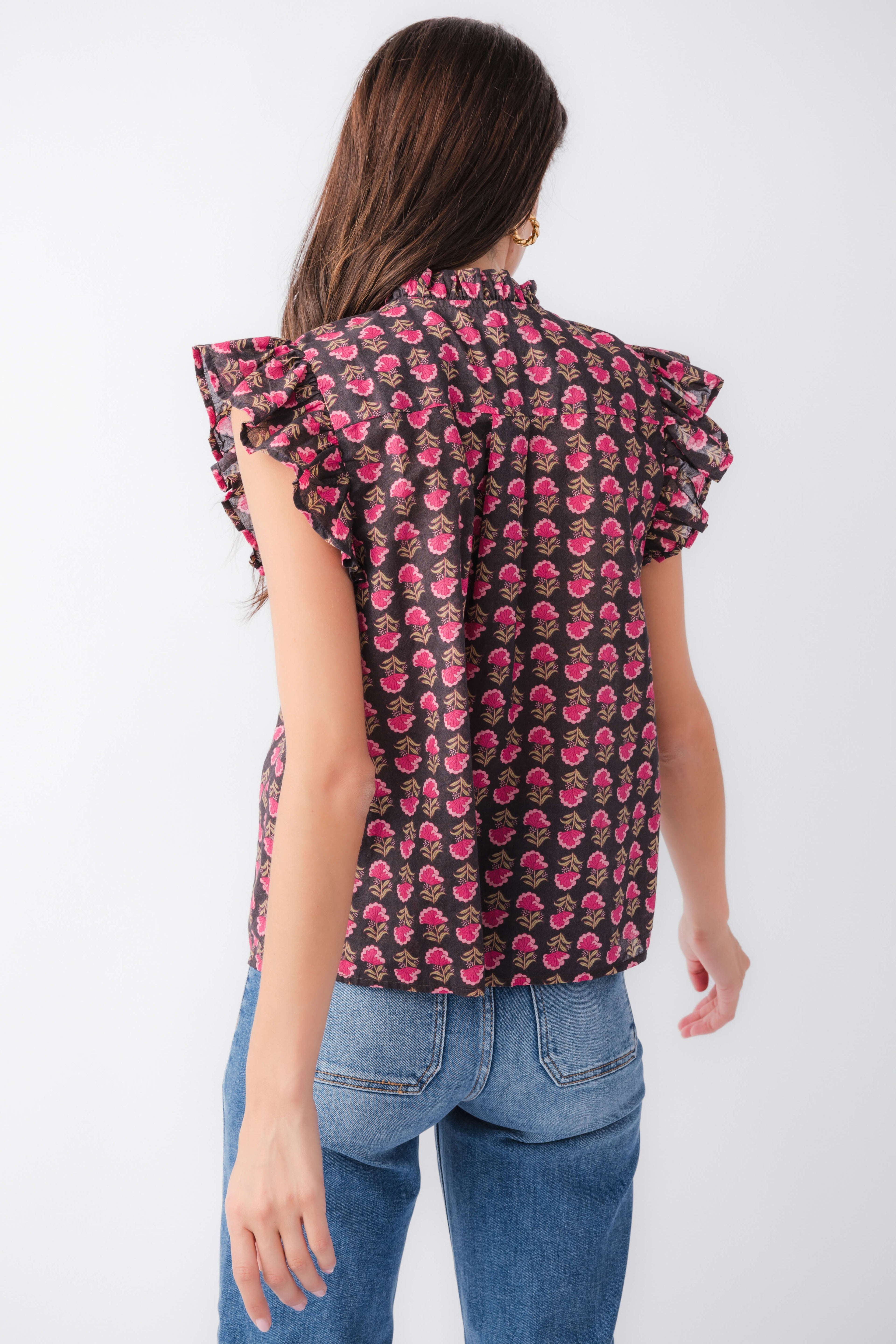 Back view of flutter sleeve button-up top with dark base and pink block print pattern