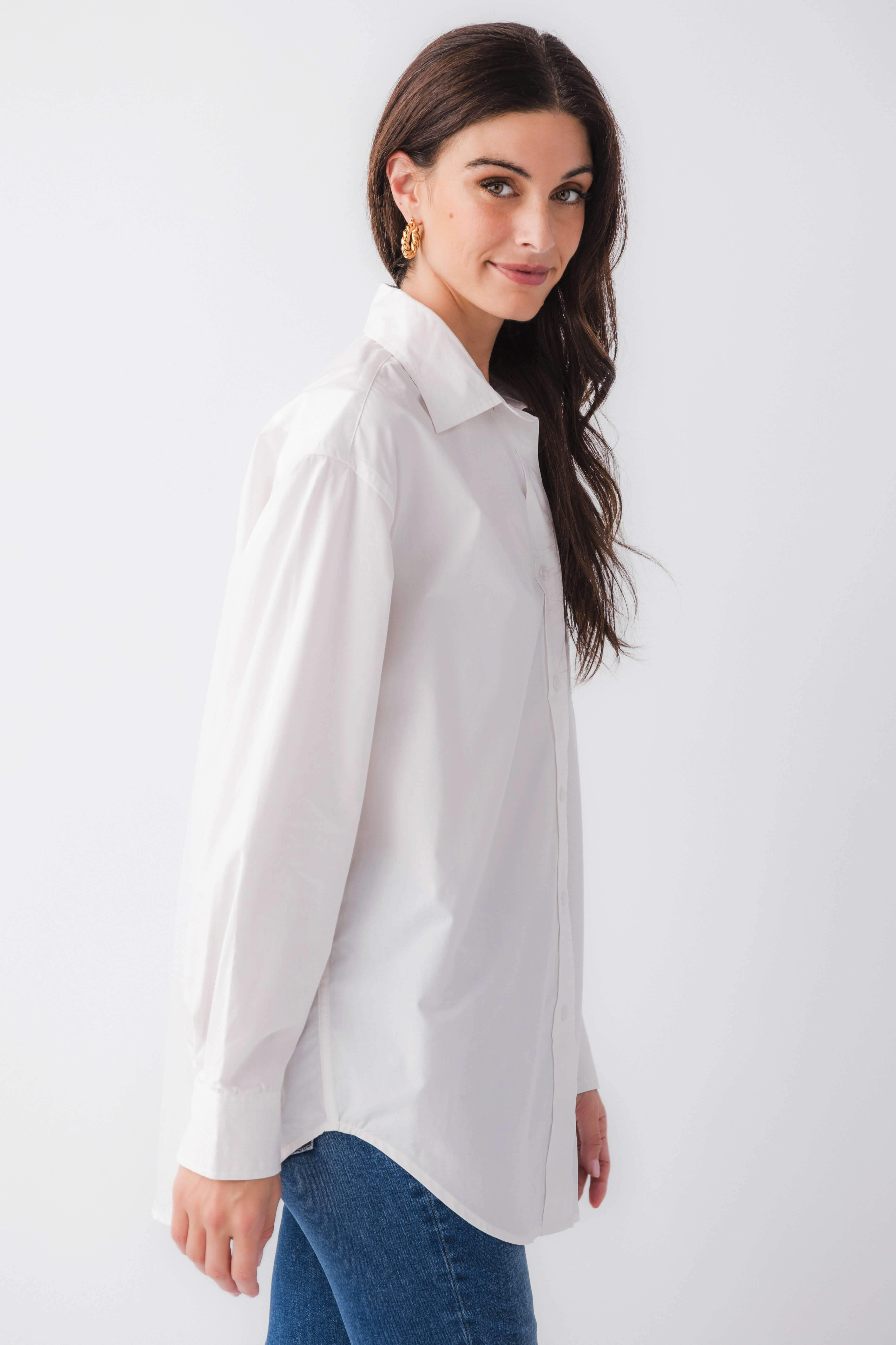 White poplin button-down top with pointed collar, long sleeves, and curved hem