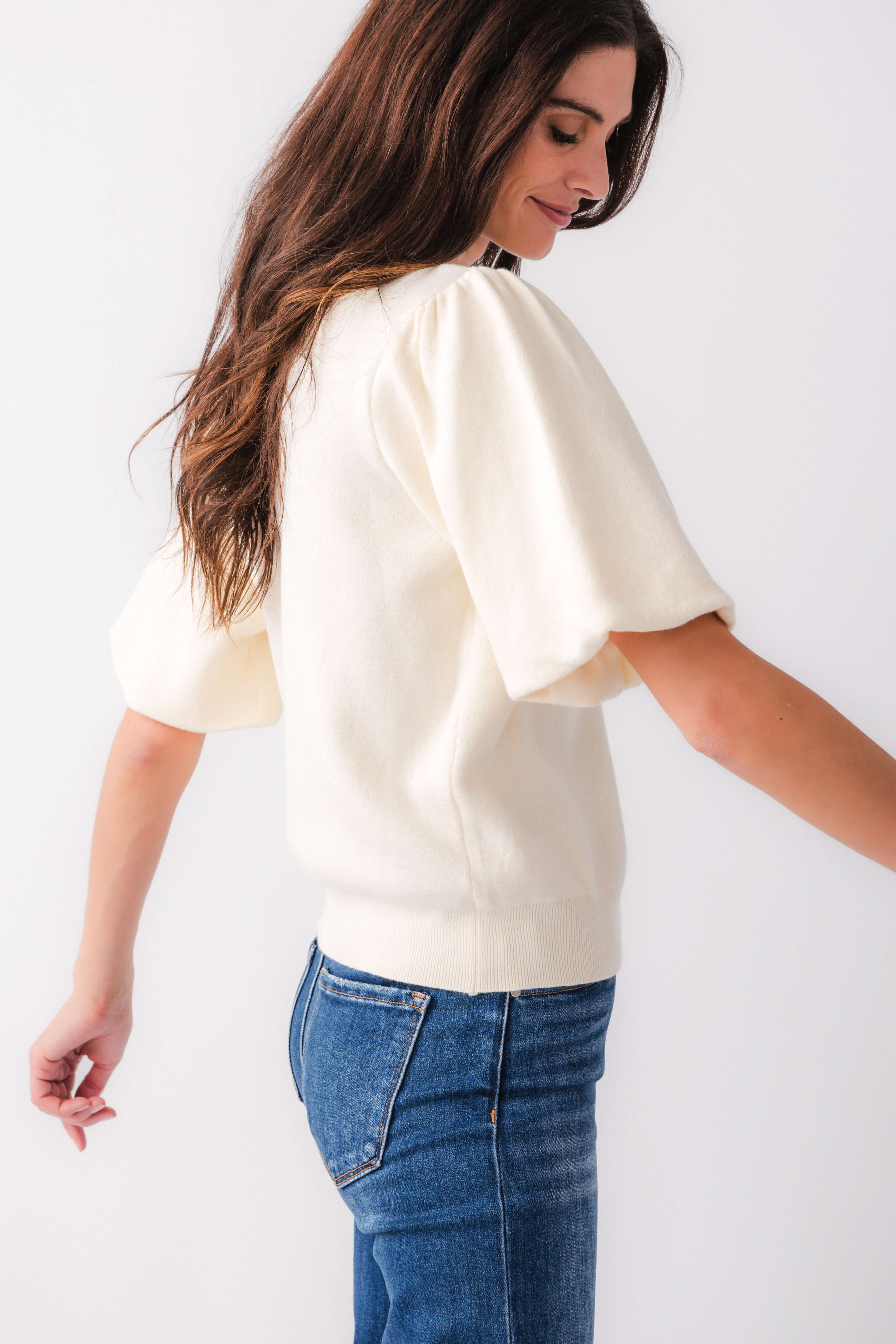 Cream knit bubble-sleeve top shown from the side, crew neckline