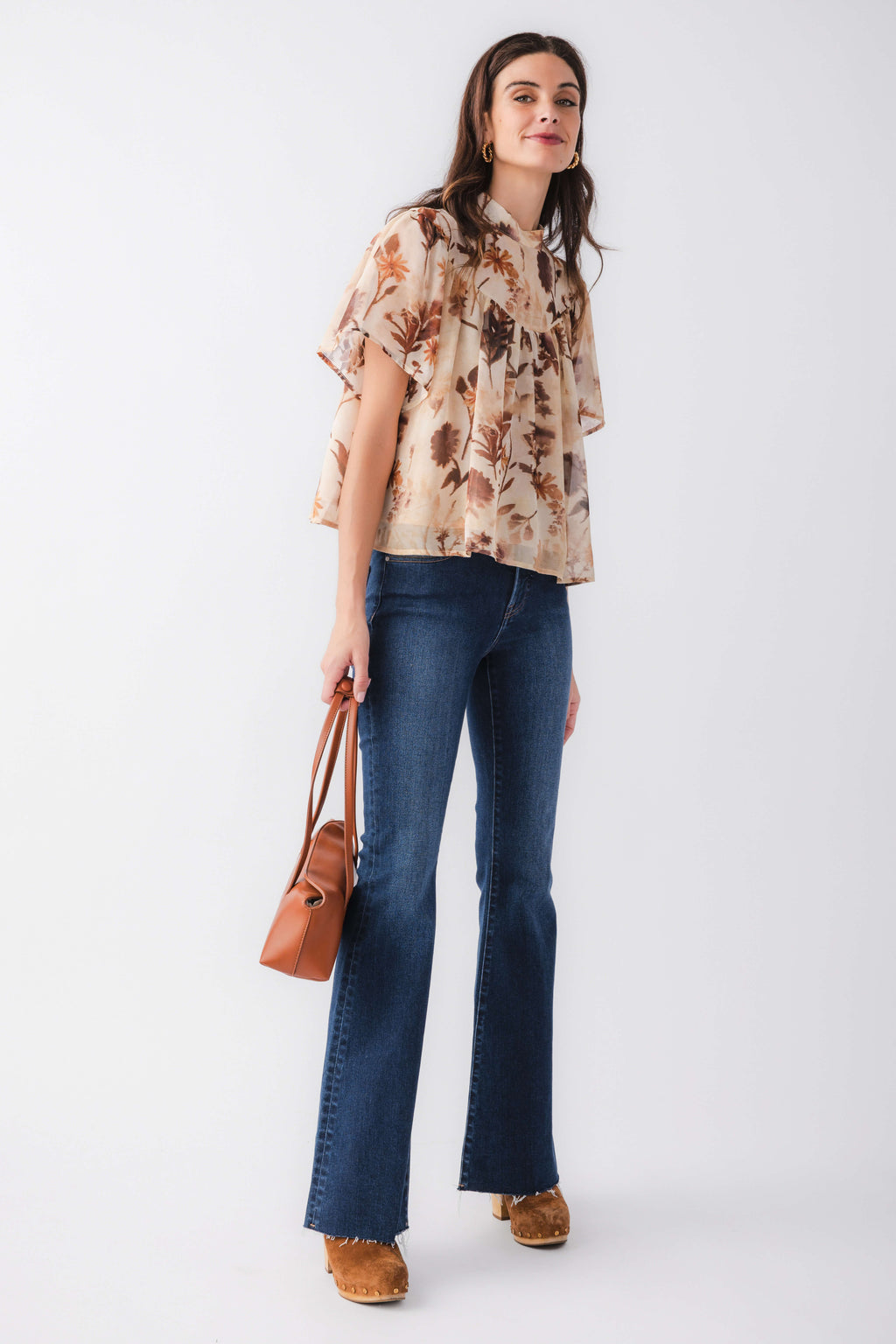 Tan floral blouse top with ruffled neckline, paired with blue flared jeans