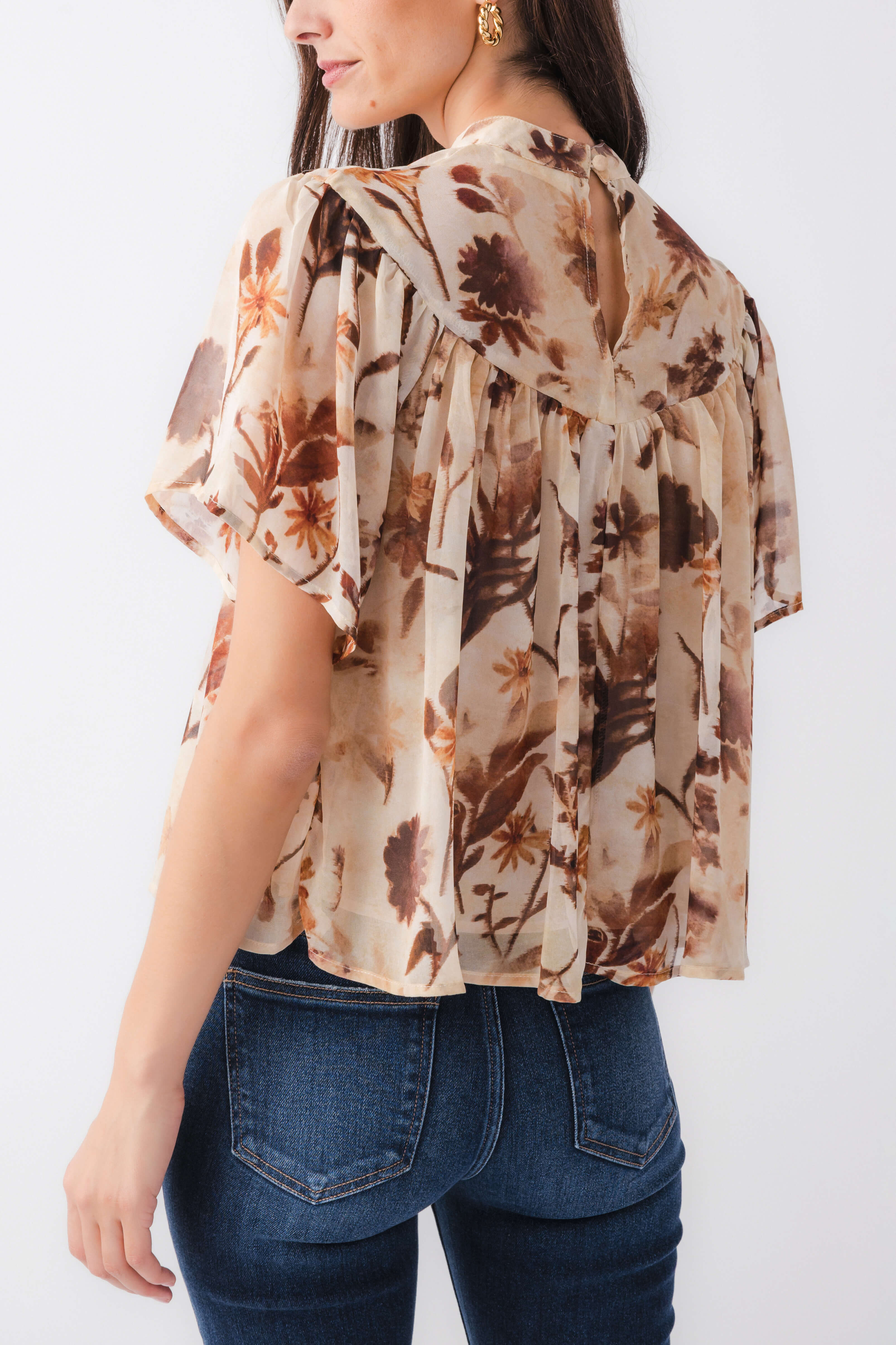 Tan floral blouse top with relaxed fit and ruffled neckline, side/back view