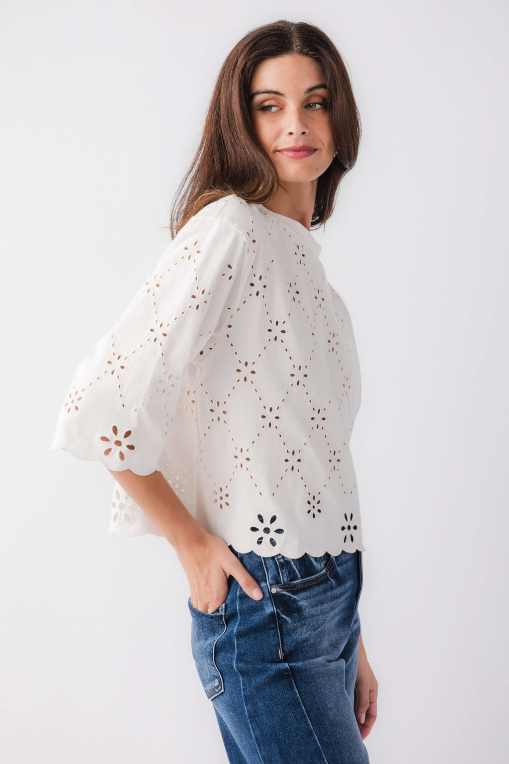 Ivory eyelet scallop top with floral cutout embroidery and scalloped hem, angled front view