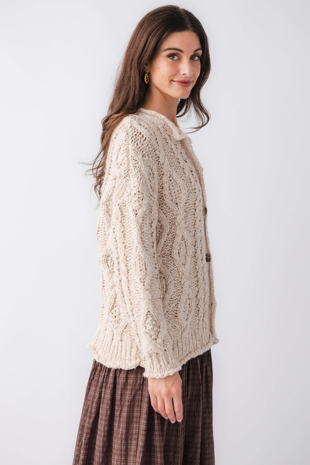 Cream cable-knit cardigan with button front and long sleeves, side view