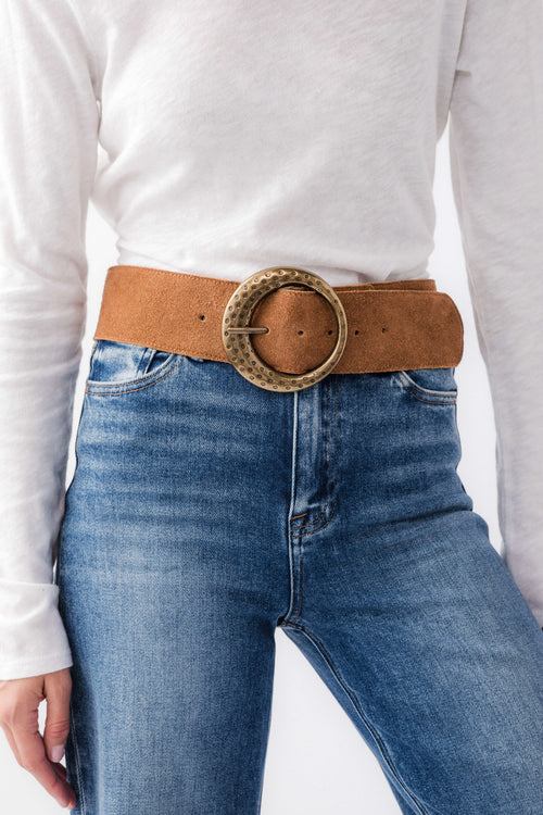 Cognac leather hip belt with round studded buckle across denim waistband