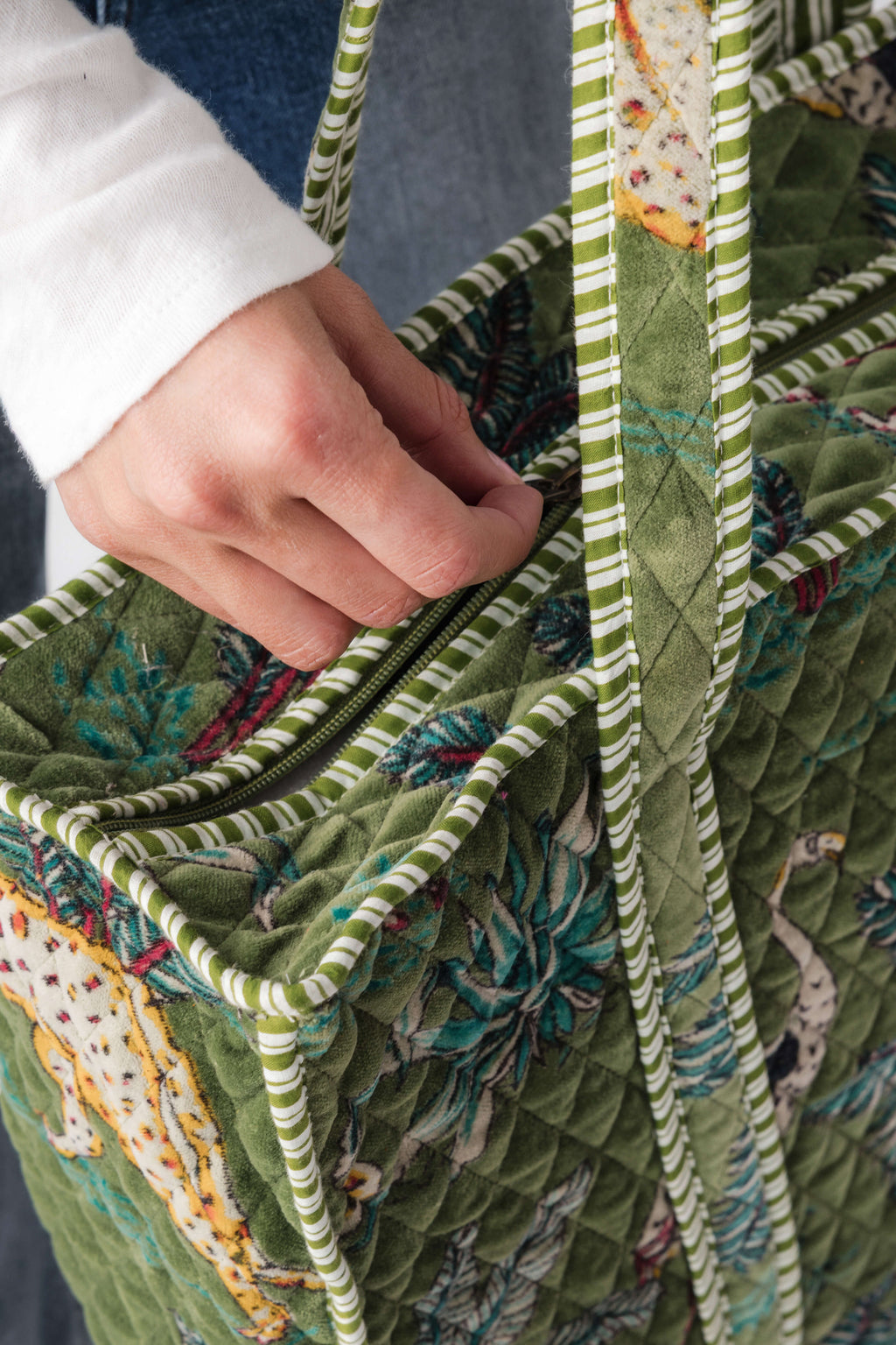 Quilted green tote with stitched pattern, striped rope handles, visible zipper