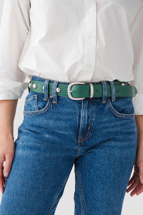 Emerald stud belt with square buckle and gold eyelets, worn on jeans