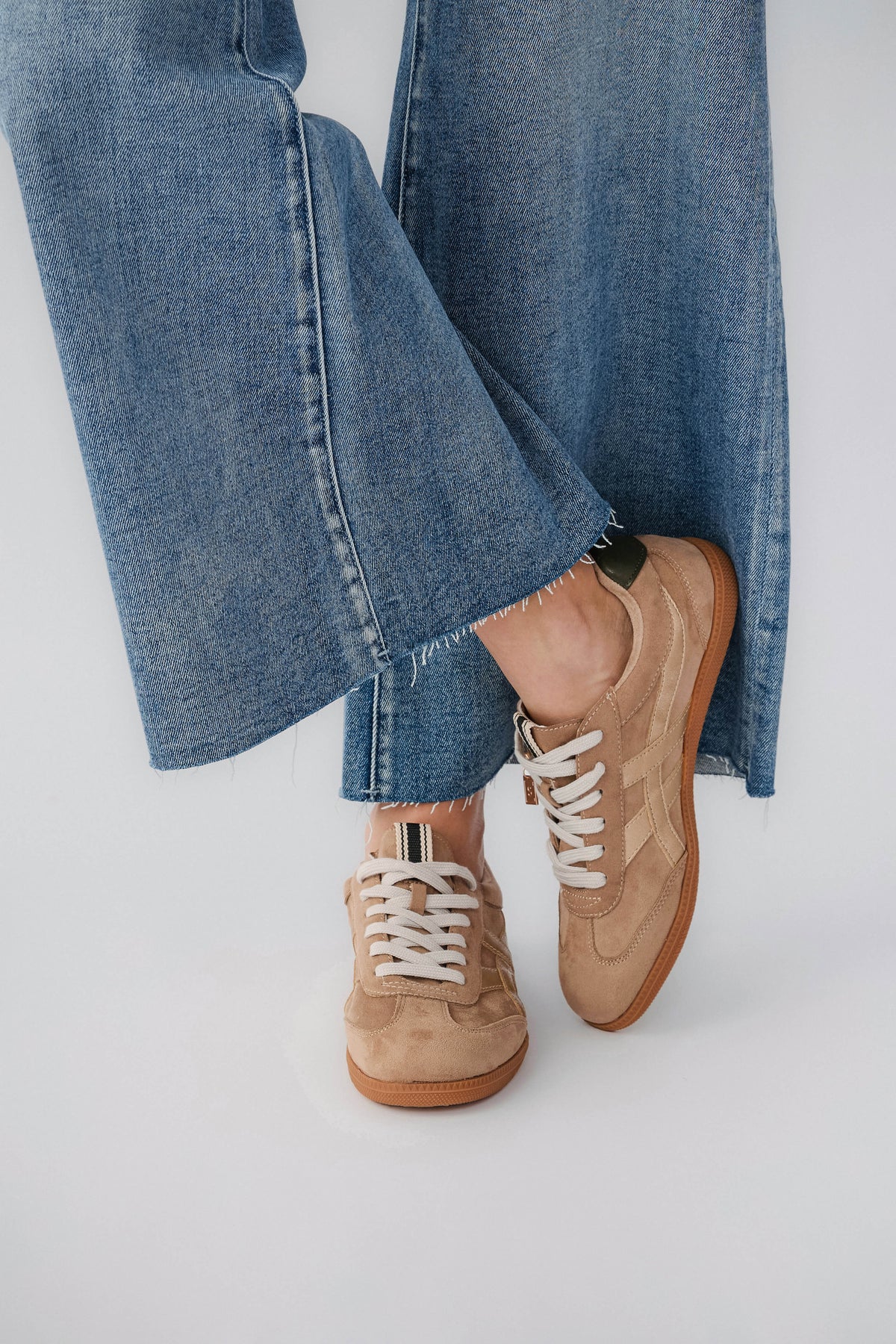 Mink suede low-top sneaker with white lace-up, gum sole, worn with cuffed jeans