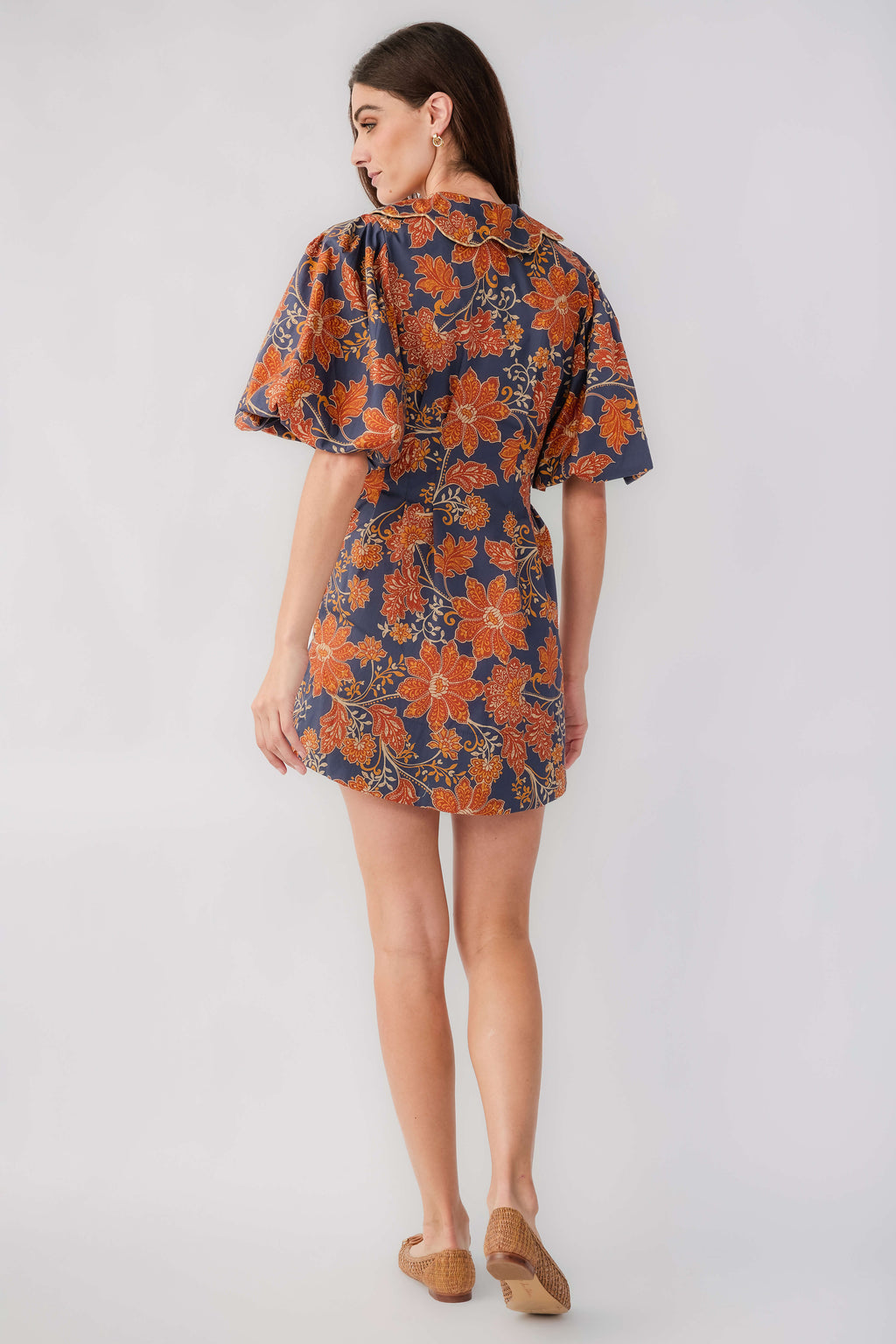 Back view of floral printed short dress in dark navy with rust, flutter sleeves