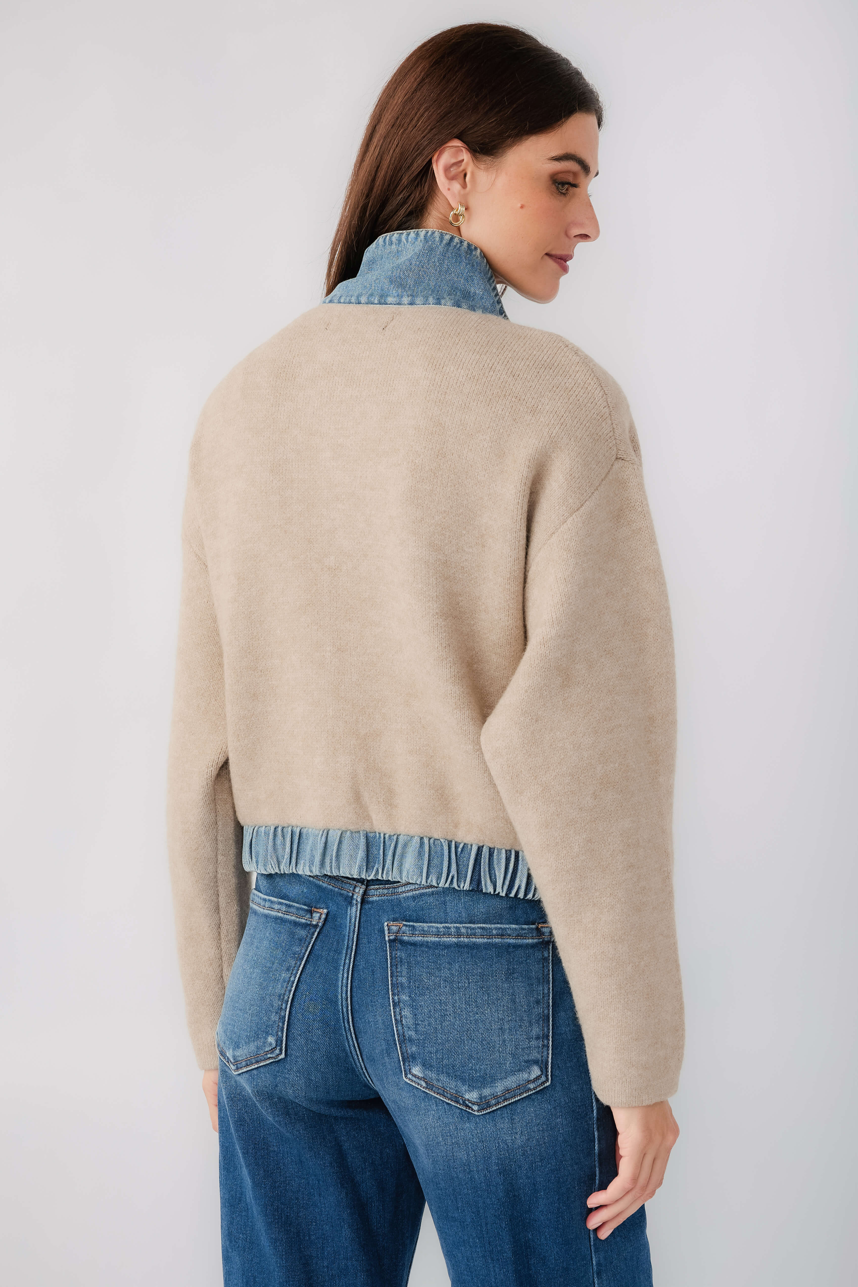Tan sweater bomber jacket with blue ribbed hem and back seams, side view