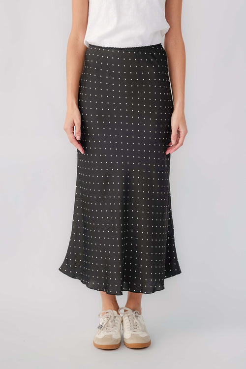 Black satin midi skirt with small white polka dots and flowy hem