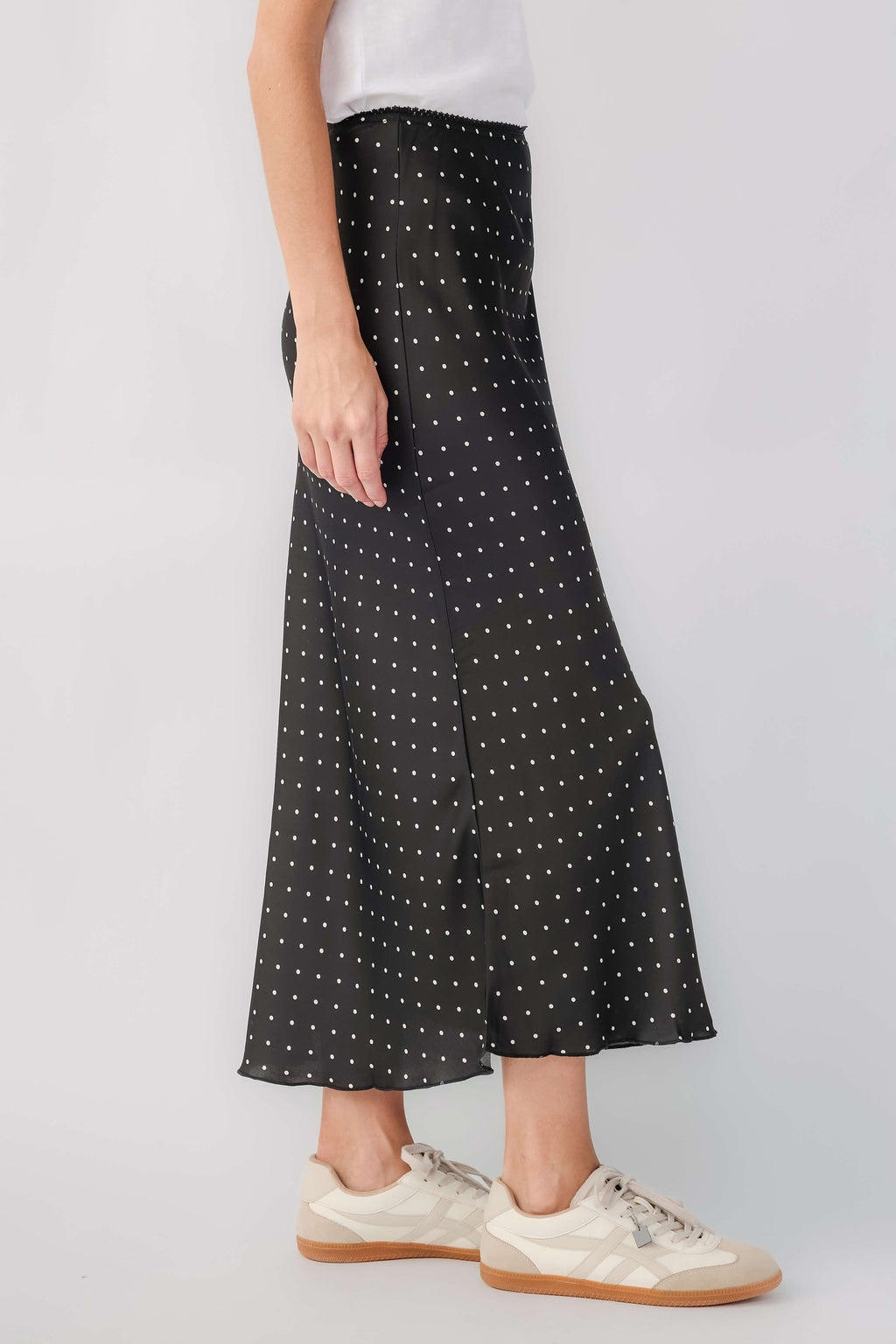 Black satin midi skirt with small white polka dots, side view