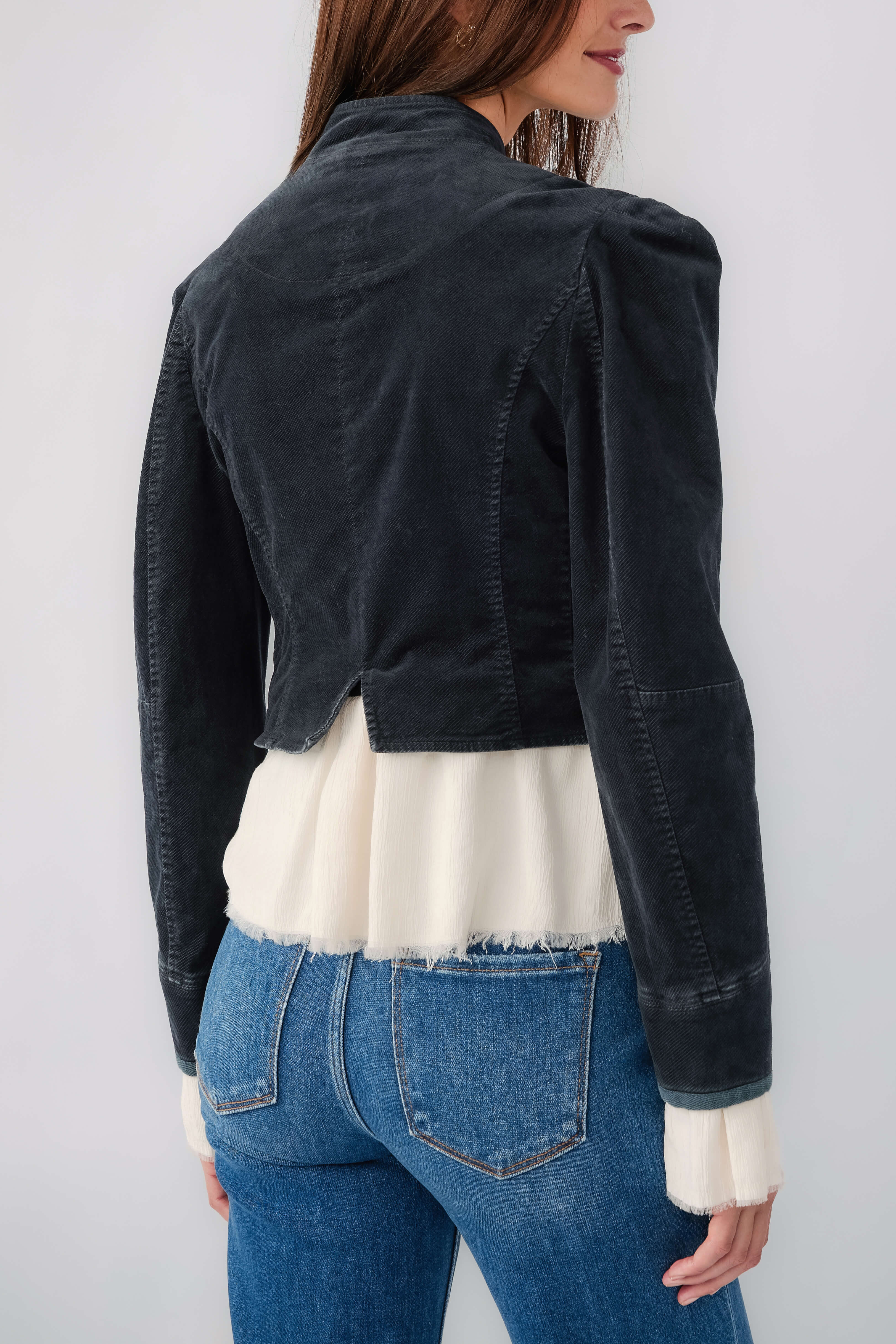Black denim blazer back view with seams and white ruffled hem