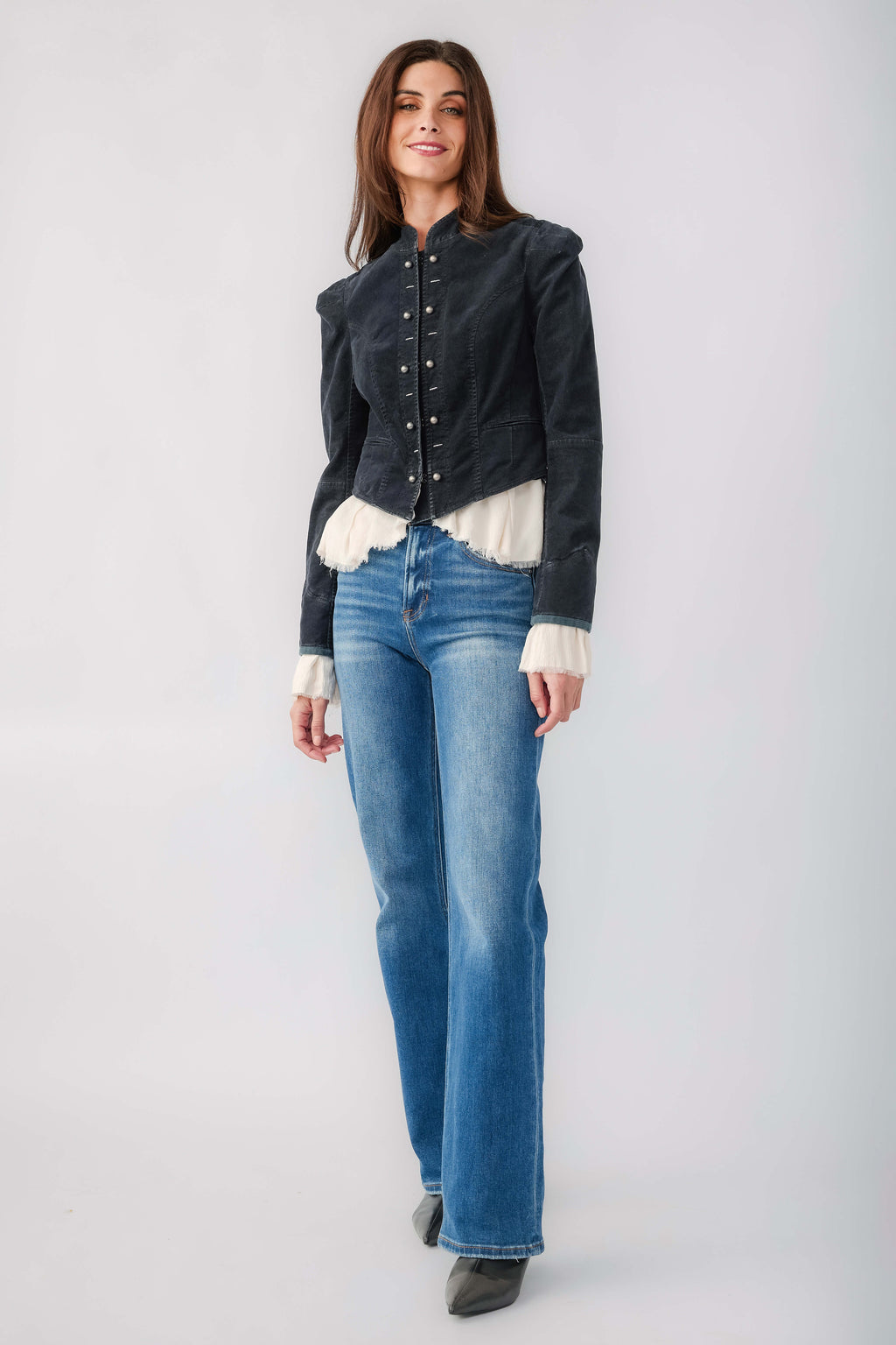 Black denim blazer with button front and white ruffle cuffs, paired with jeans