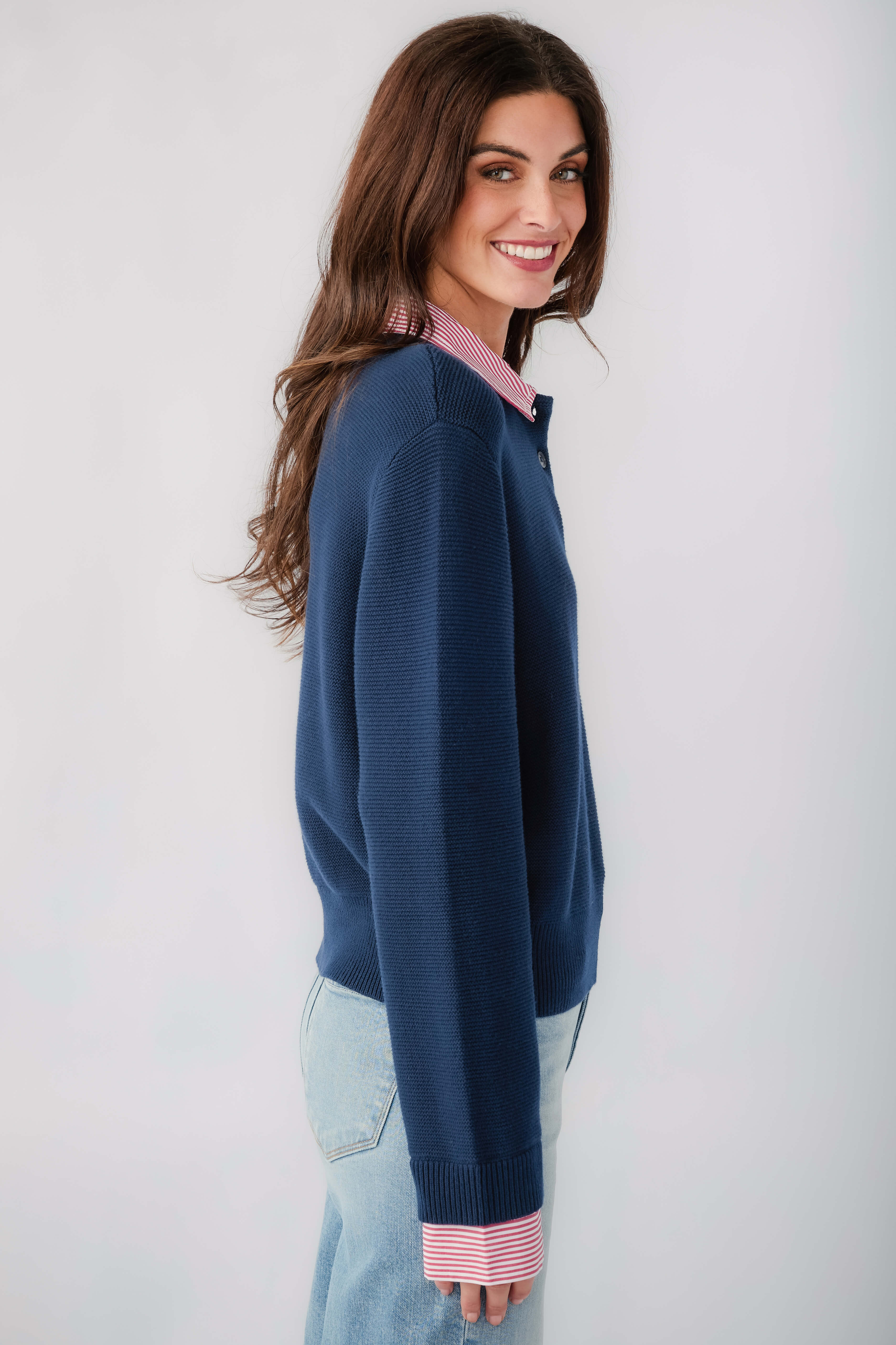 Navy knit sweater with striped cuffs and button placket, side view