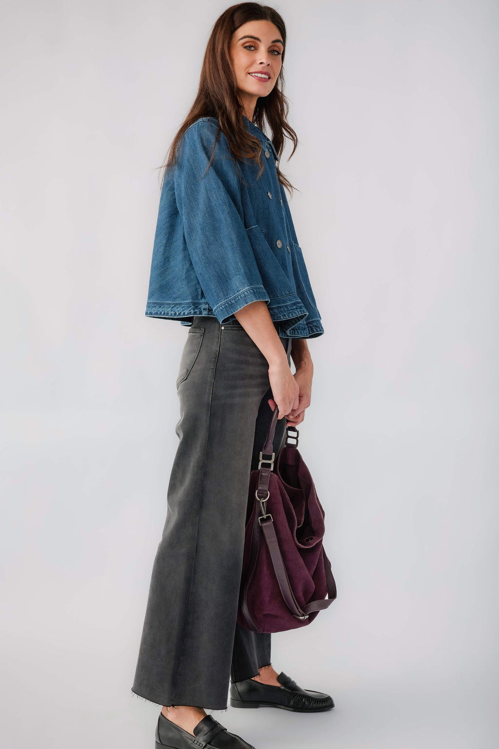 Dark blue cropped denim jacket with 3/4 sleeves and button front, side profile