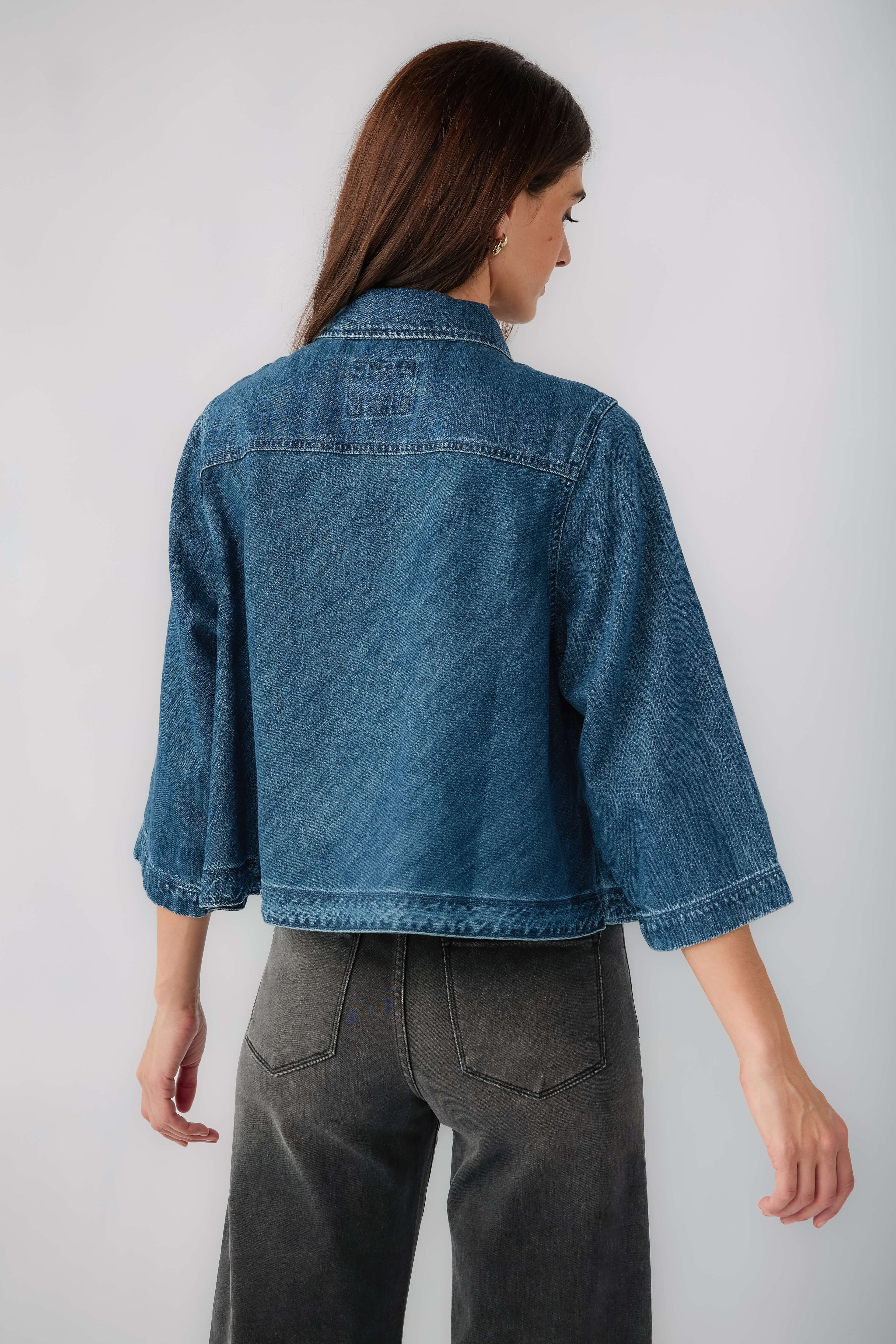 Dark blue cropped denim jacket back view with yoke seams and button placket