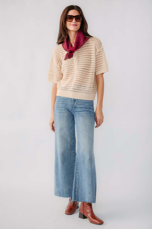 Cream open-knit polo sweater with short sleeves and collared neckline, front view