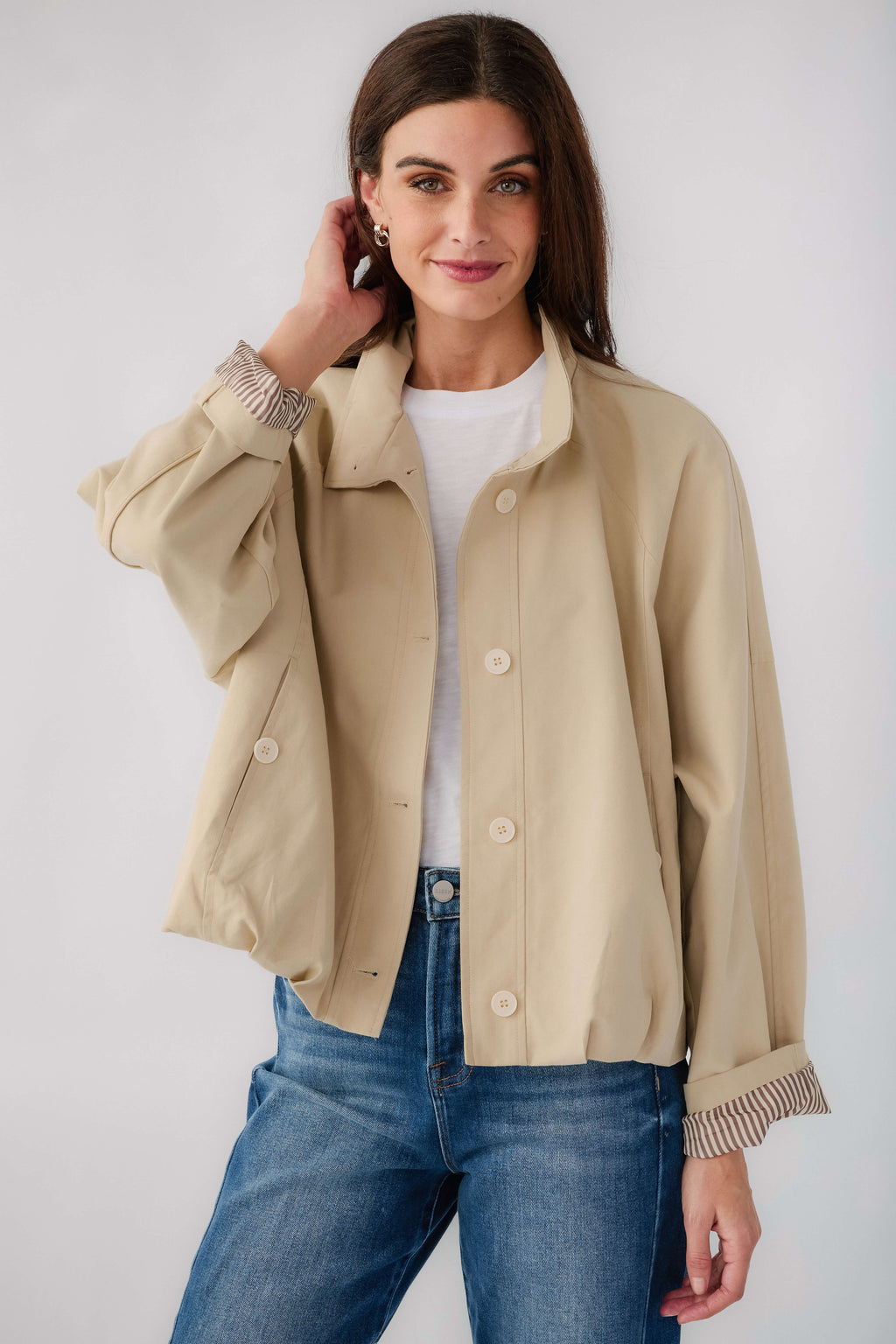 Light beige short jacket with button front, stand collar, and striped ribbed cuffs