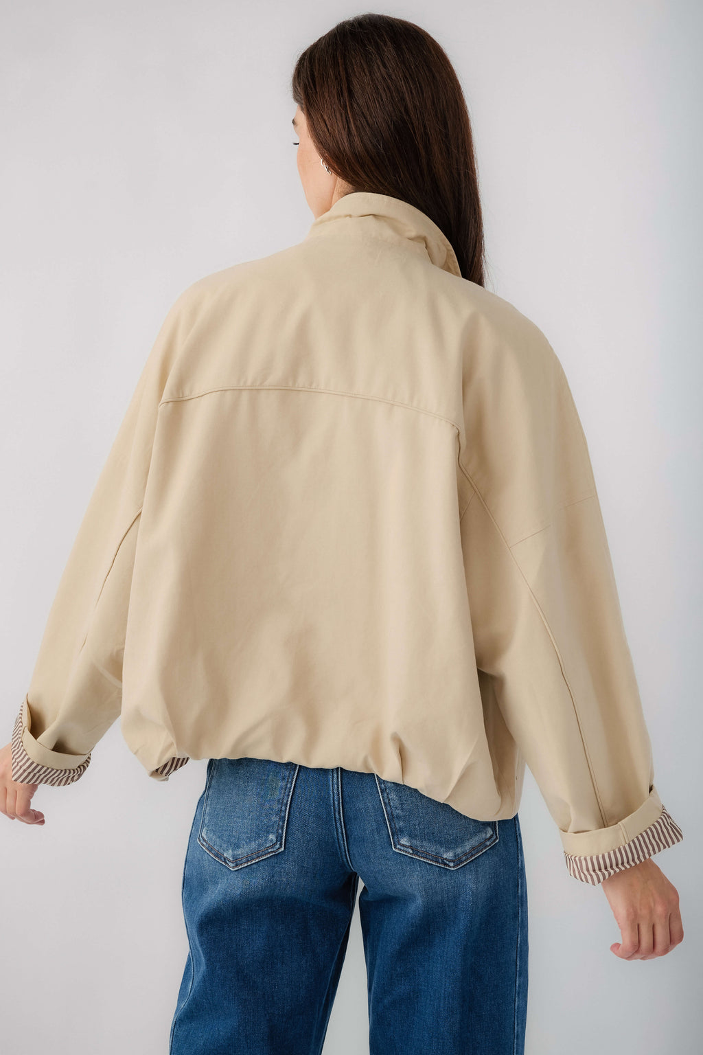 Light beige jacket from back, stand collar, button closures, striped ribbed cuffs