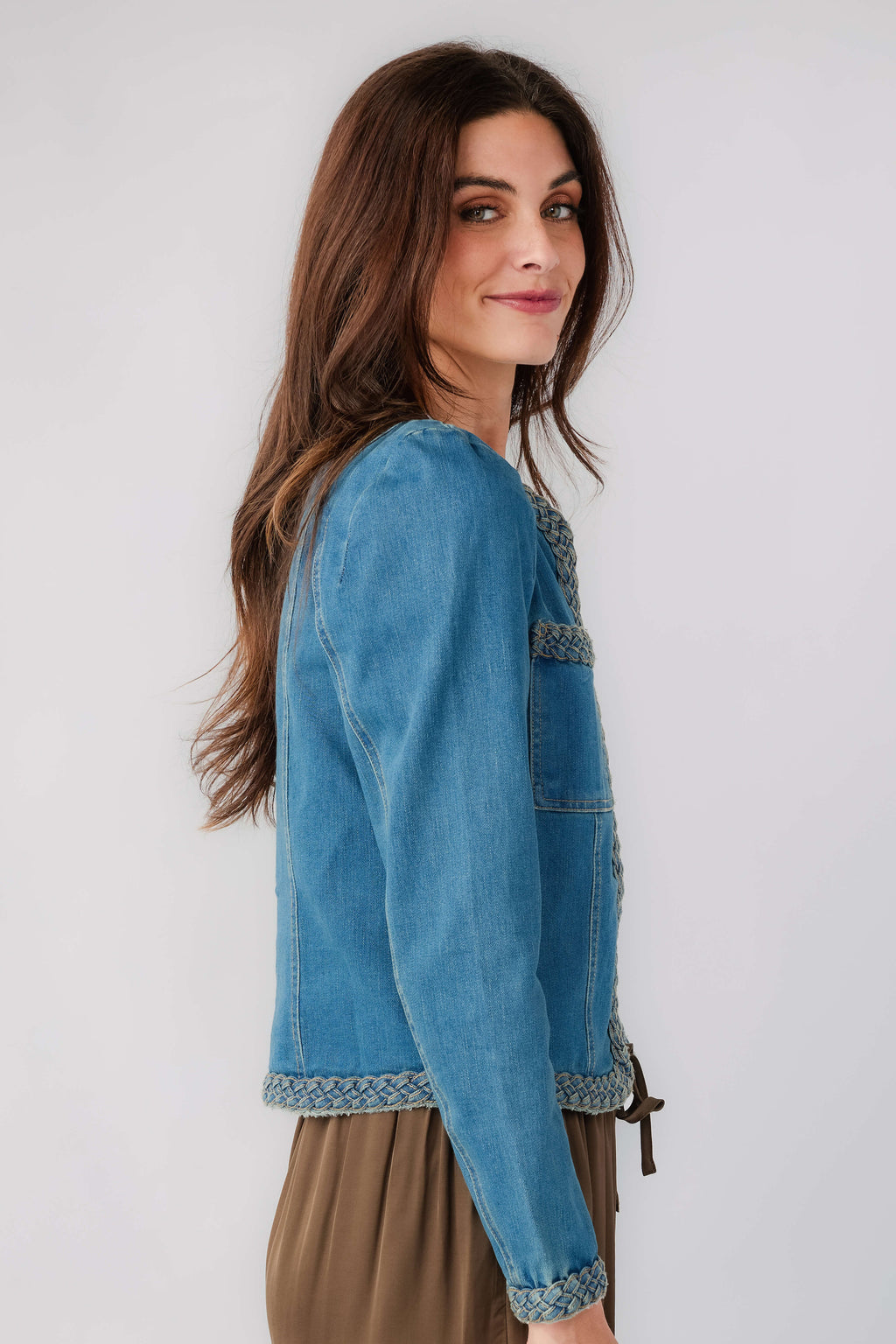 Medium wash denim jacket with braided trim along cuffs and flap pockets