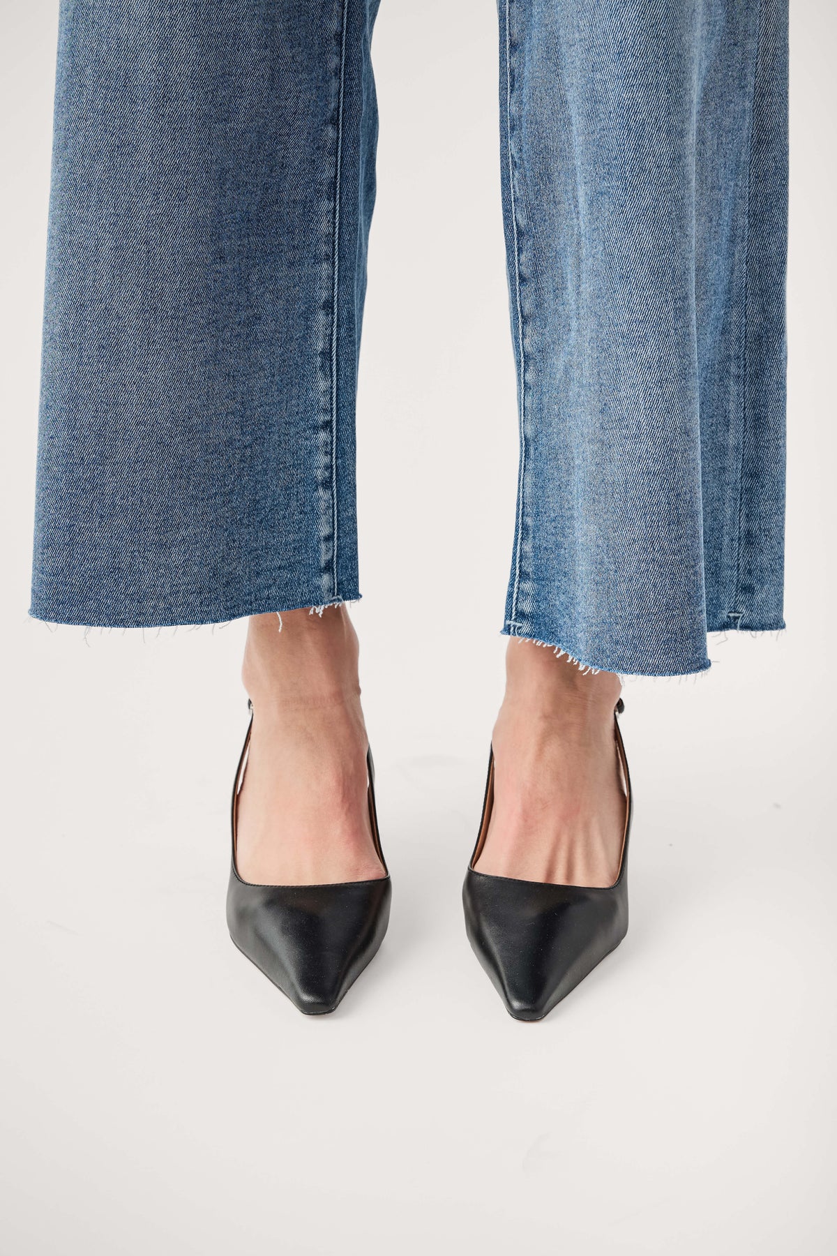 Black leather slingback pump with pointed toe and slim high heel, worn with jeans.