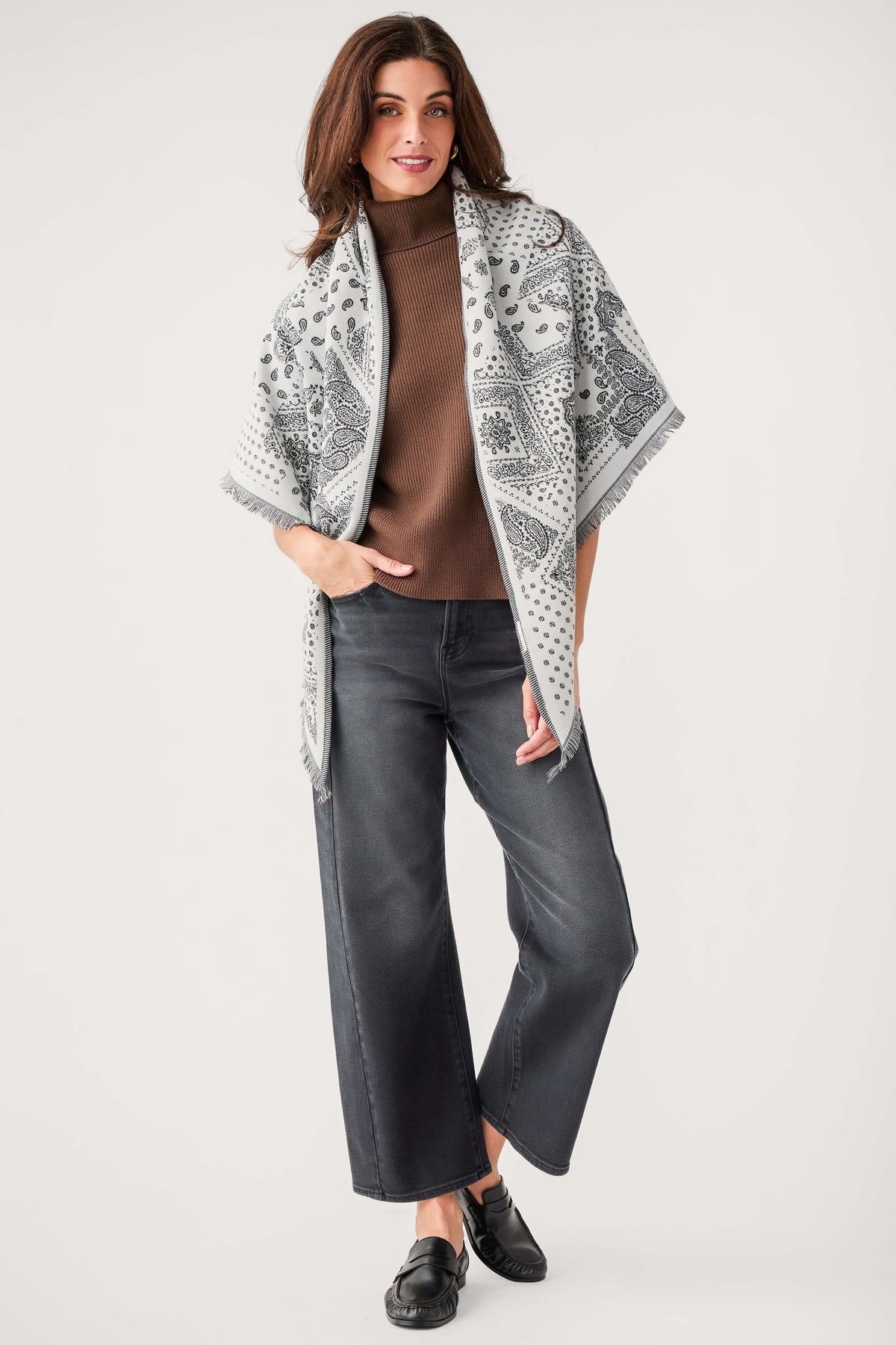 White bandana print scarf with dark pattern and fringe, worn over shoulders