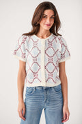 Ivory short-sleeve sweater top with button placket and red-blue floral diamond pattern
