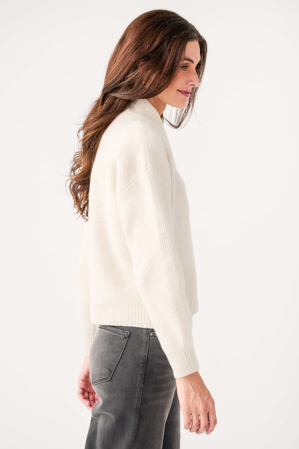 Cream shawl-collar knit sweater with long sleeves and ribbed hem, side view