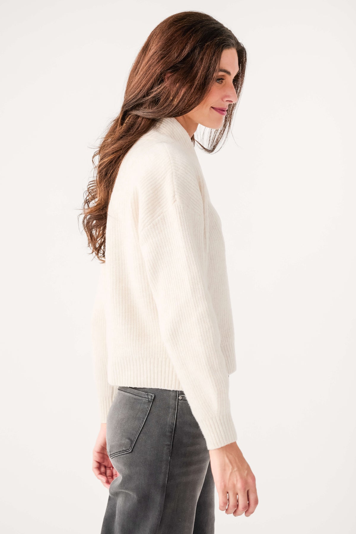 Cream shawl-collar knit sweater with long sleeves and ribbed hem, side view
