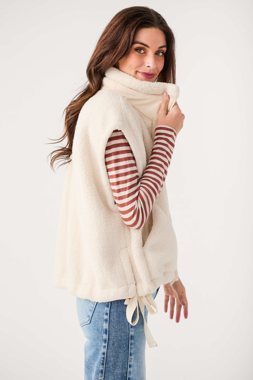 Cream fleece vest with drawstring hem and button front, side view on model.