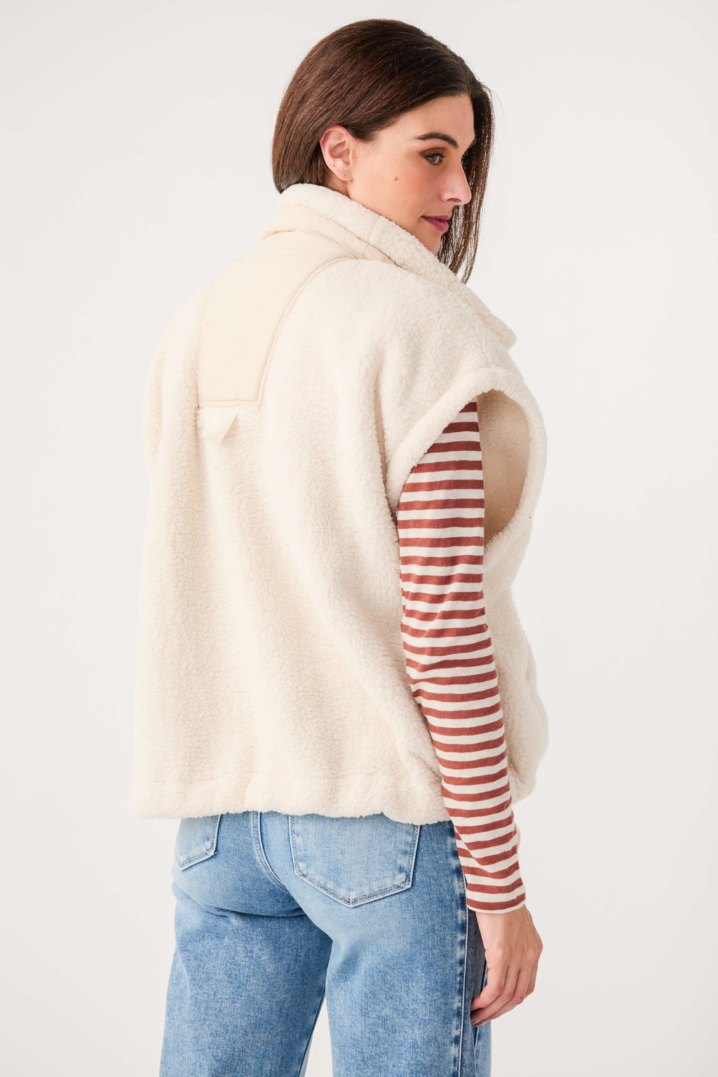 Cream fleece vest with button front and curved hem, shown from the back-left side.